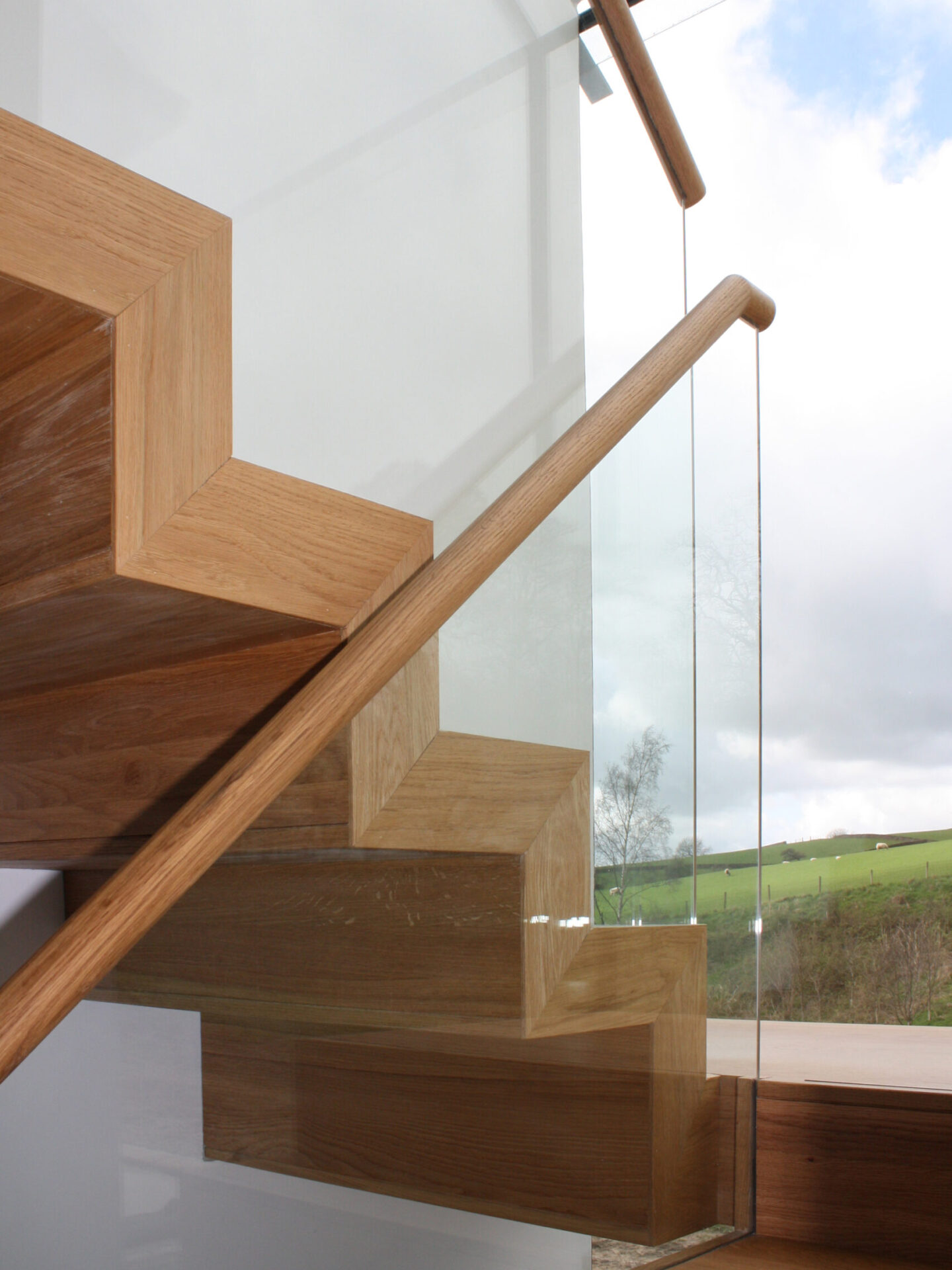 close up detail of timber staircase, timber handrail and glass balustrade