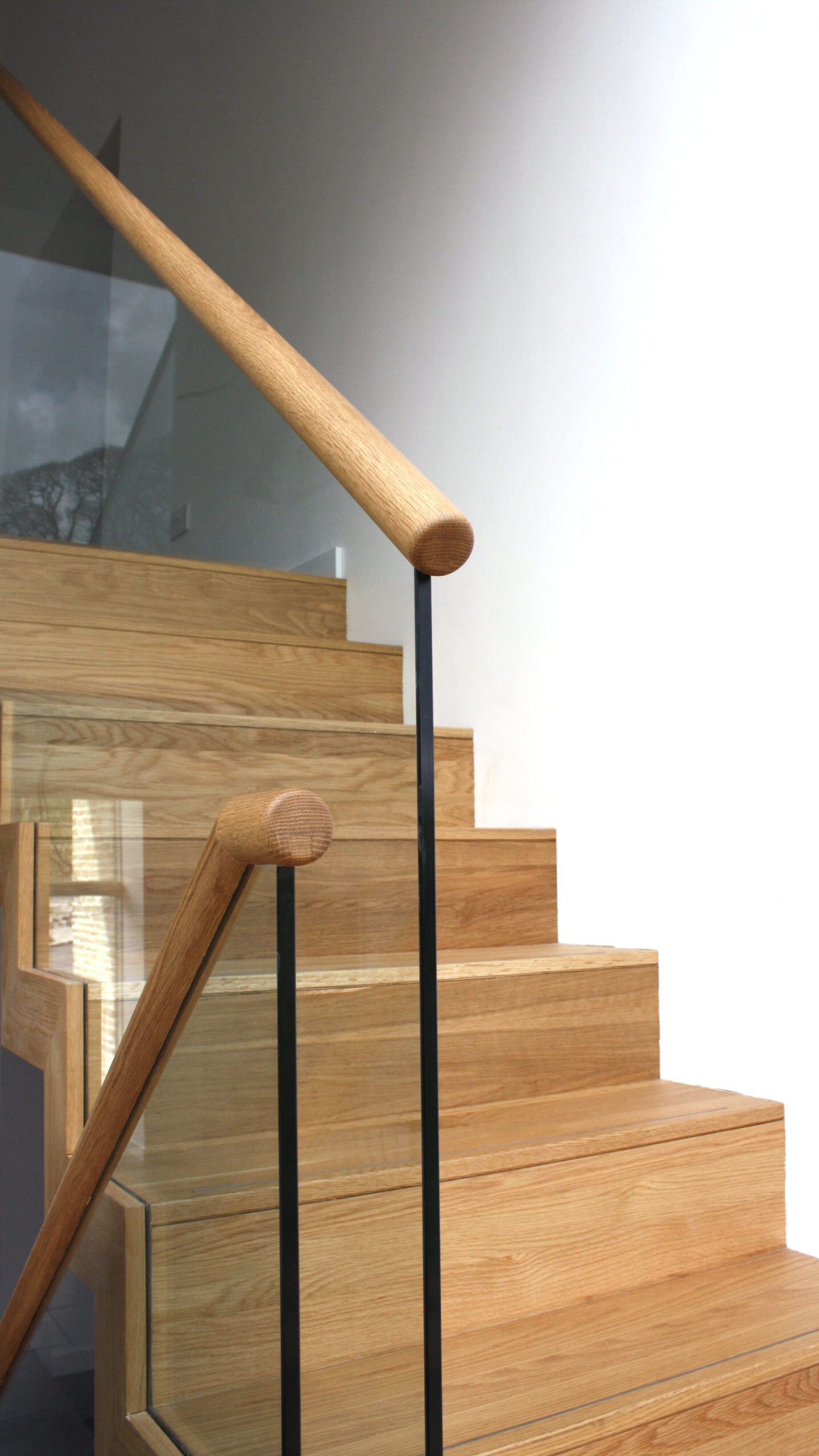 close up of wooden hand rail and glass balustrade on a timber staircase