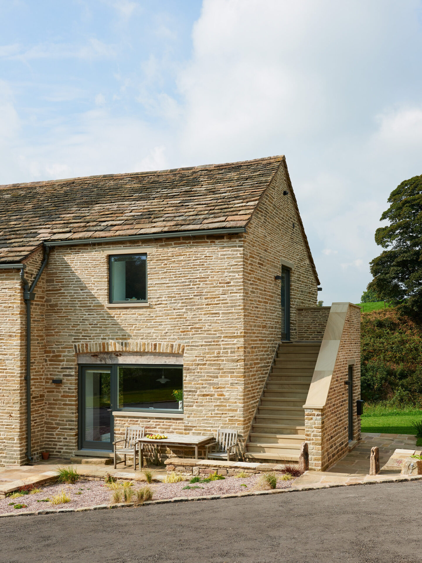 listed stone barn conversion with large glazed openings and external staircase leading up to first floor
