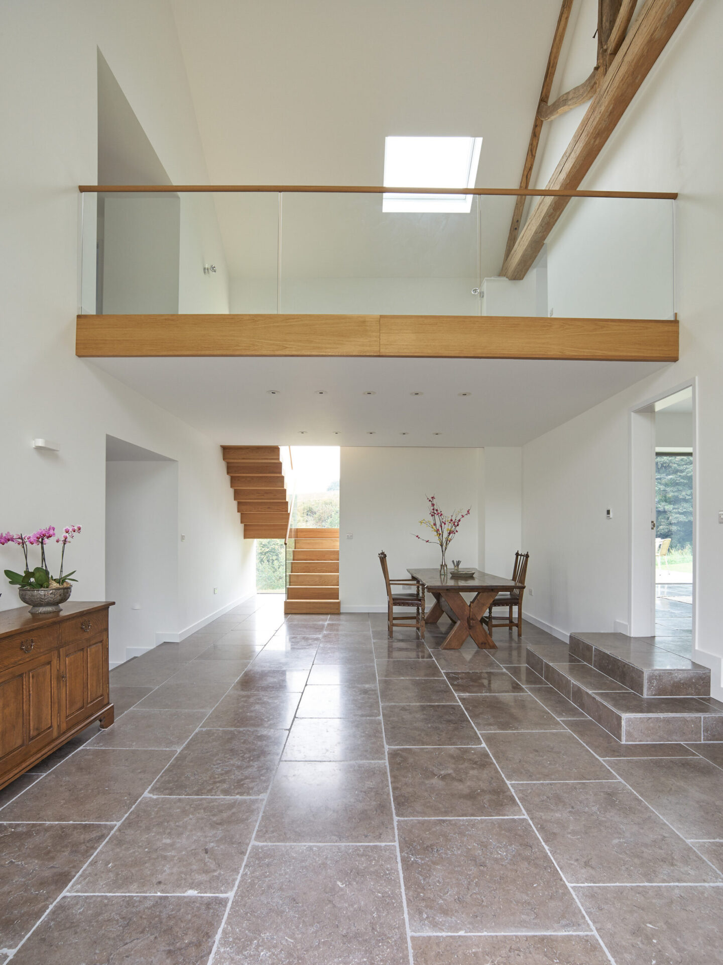 Double height entrance area of barn conversion with first floor landing and timber staircase