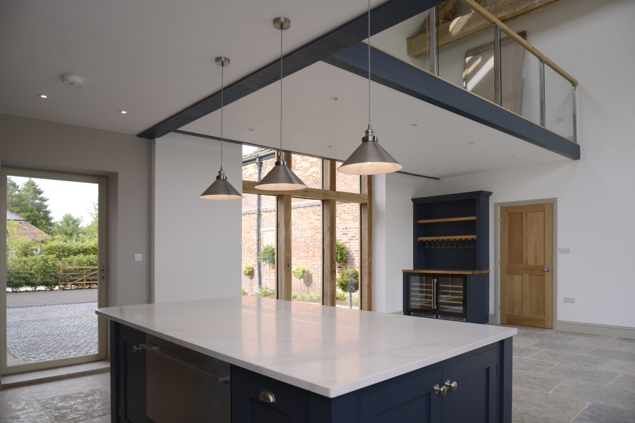kitchen with pendant lights. open plan living space behind with open first floor landing above