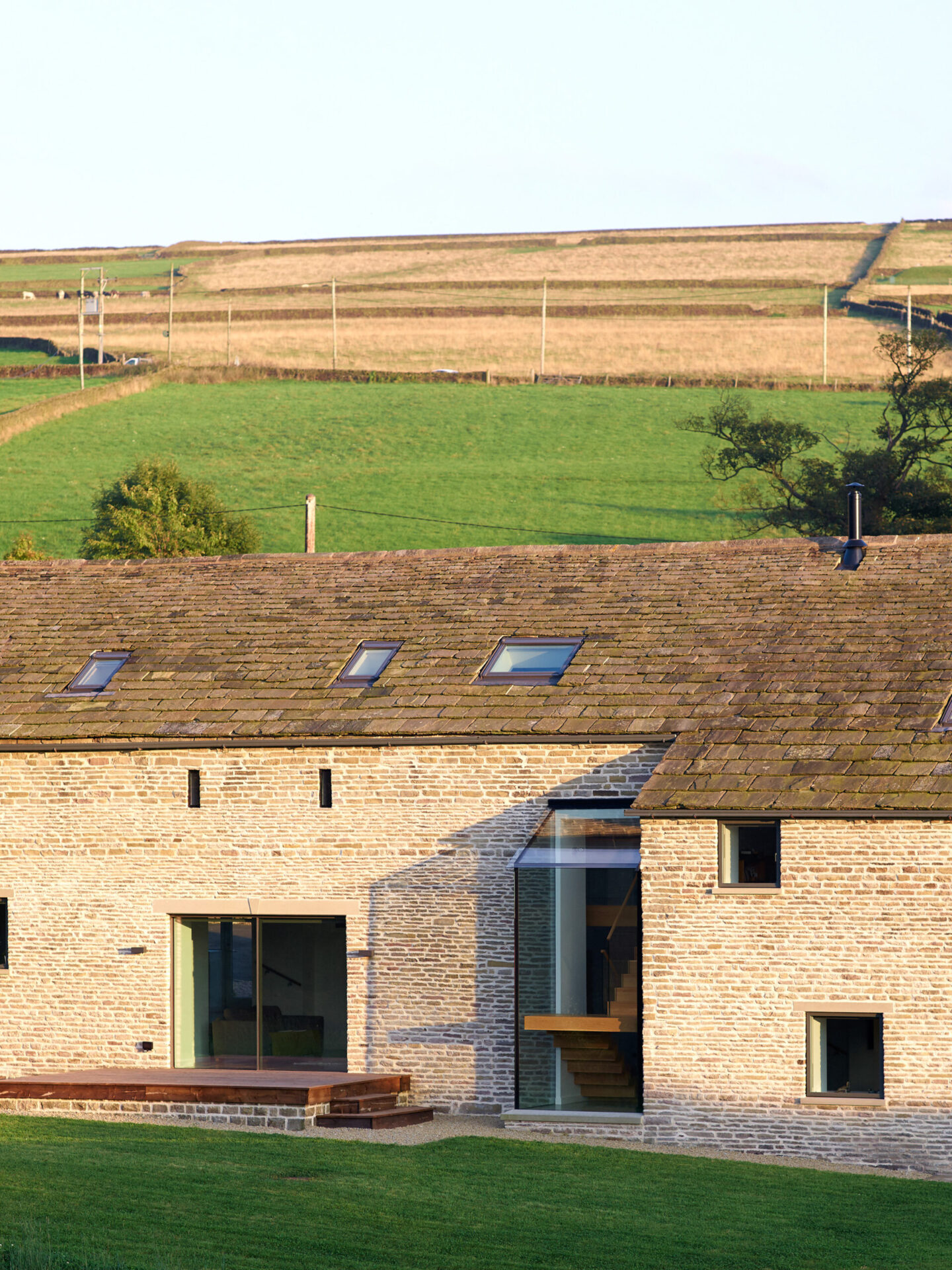 rear elevation of listed stone barn conversion with large glazed elements with the staircase visible