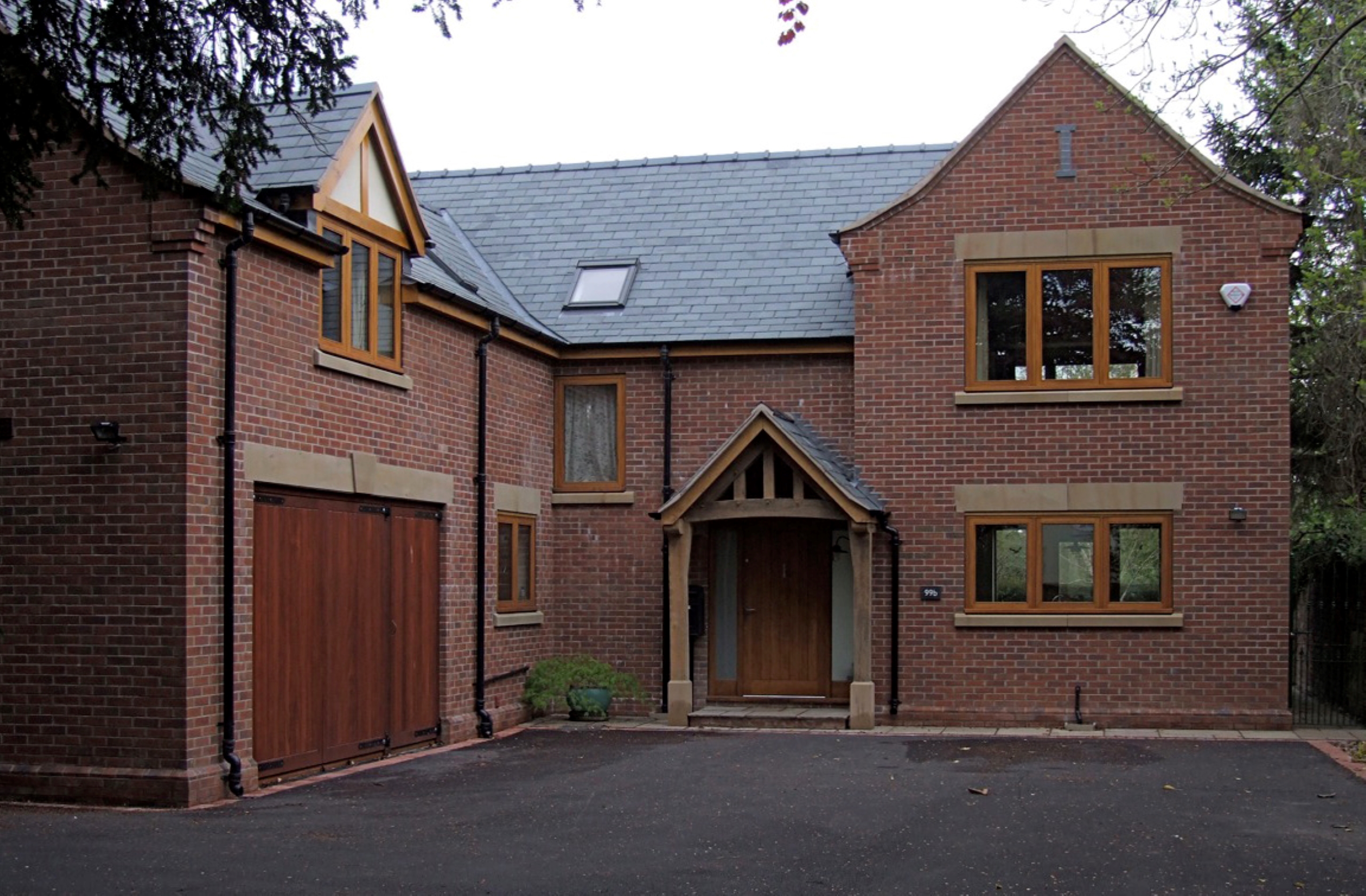 Front entrance and driveway at Byrons Lane with oak porch and oak frame glazing with stone details