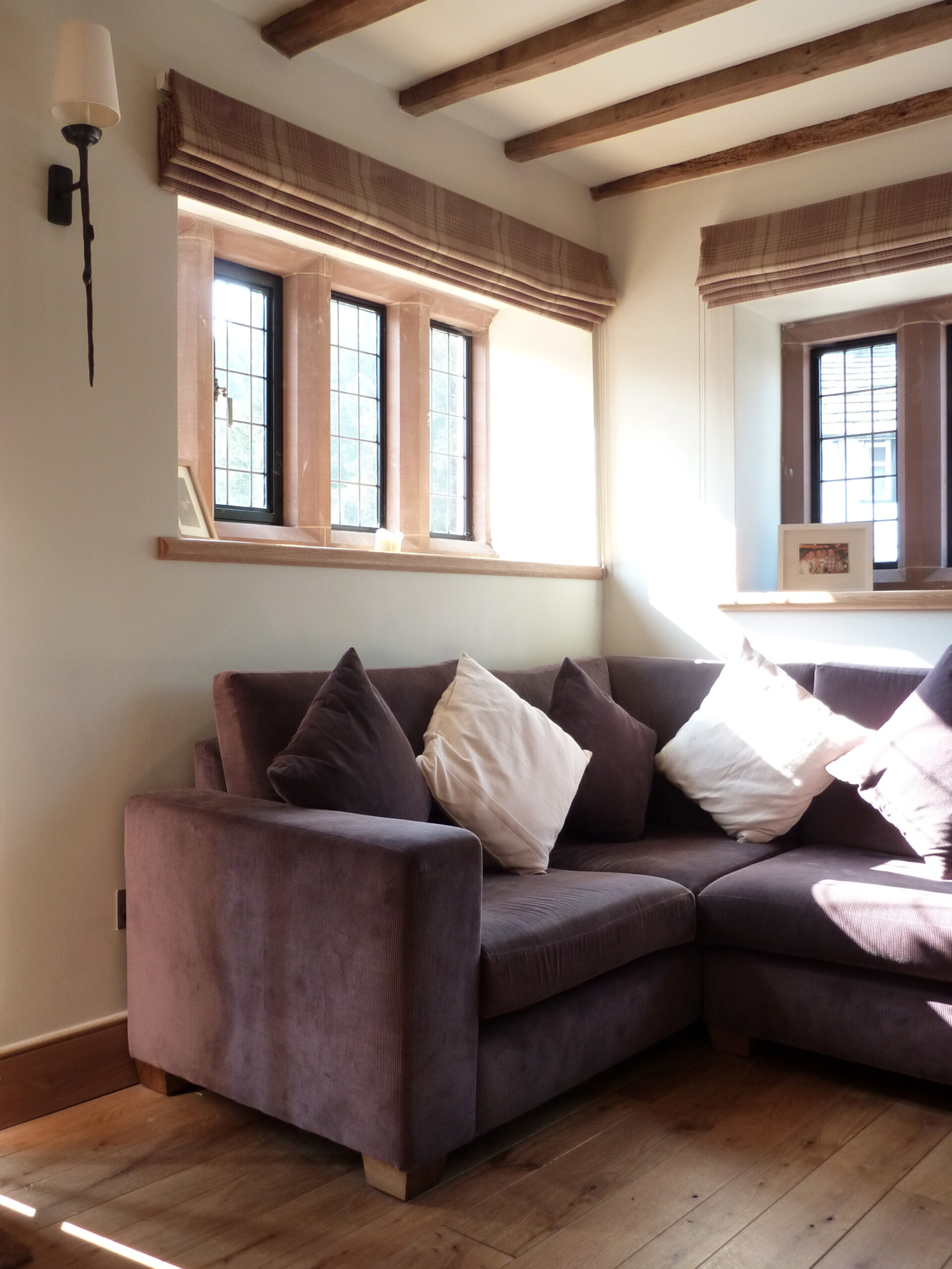 new living room with stone mullion window surrounds and exposed floor joists