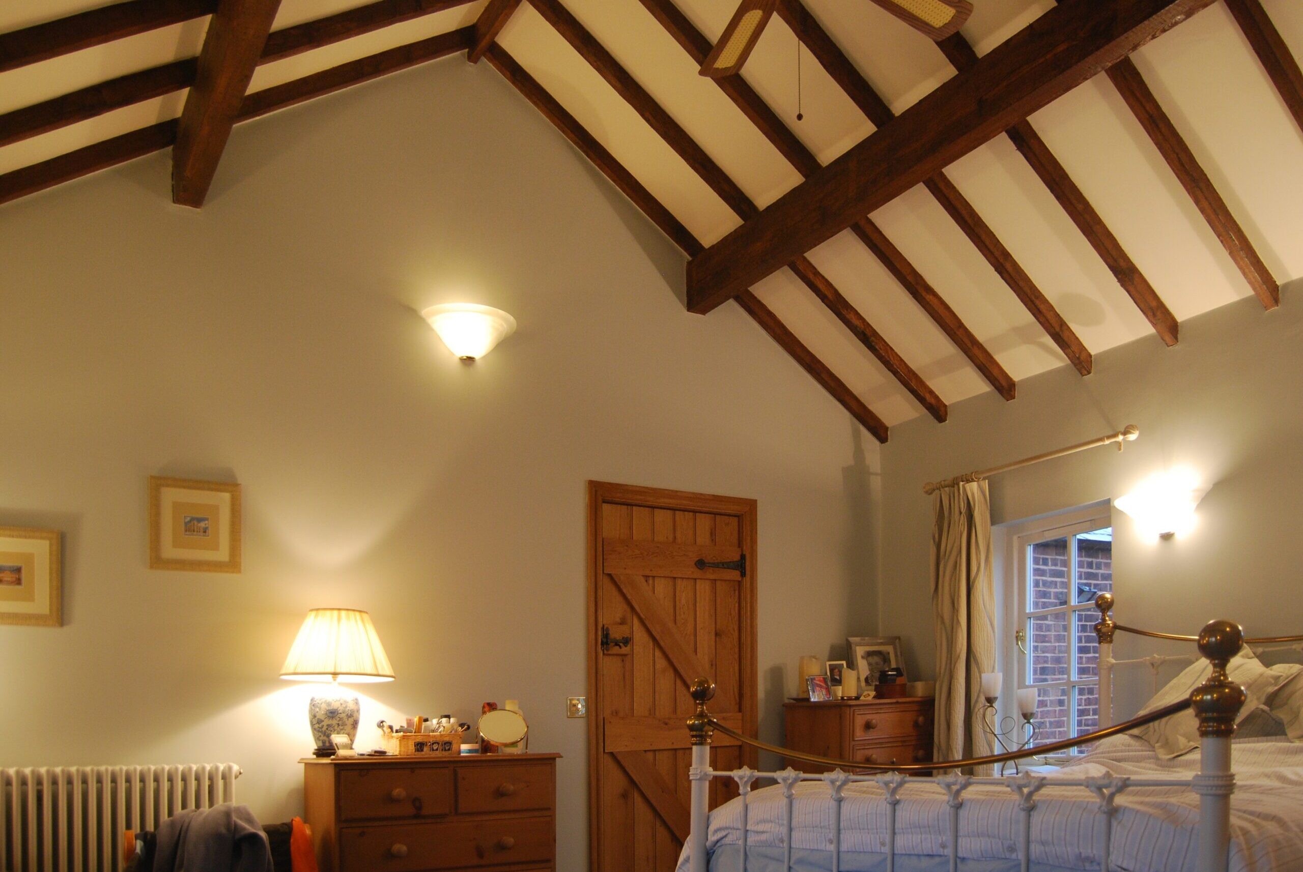 bedroom with exposed timber roof structure with plastered infill