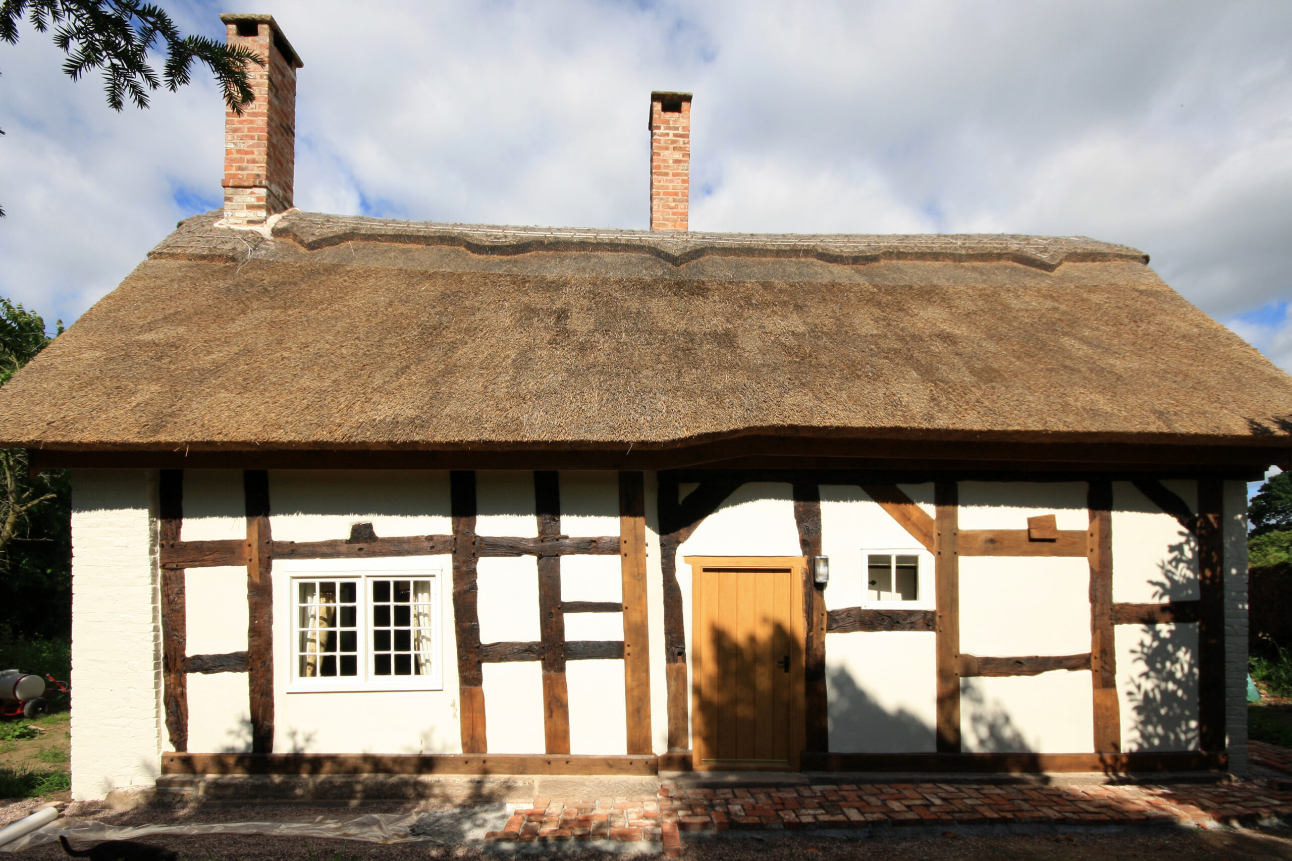 Blakehouse Cottage front elevation insulated panels infilled between existing timber structure with new thatched roof