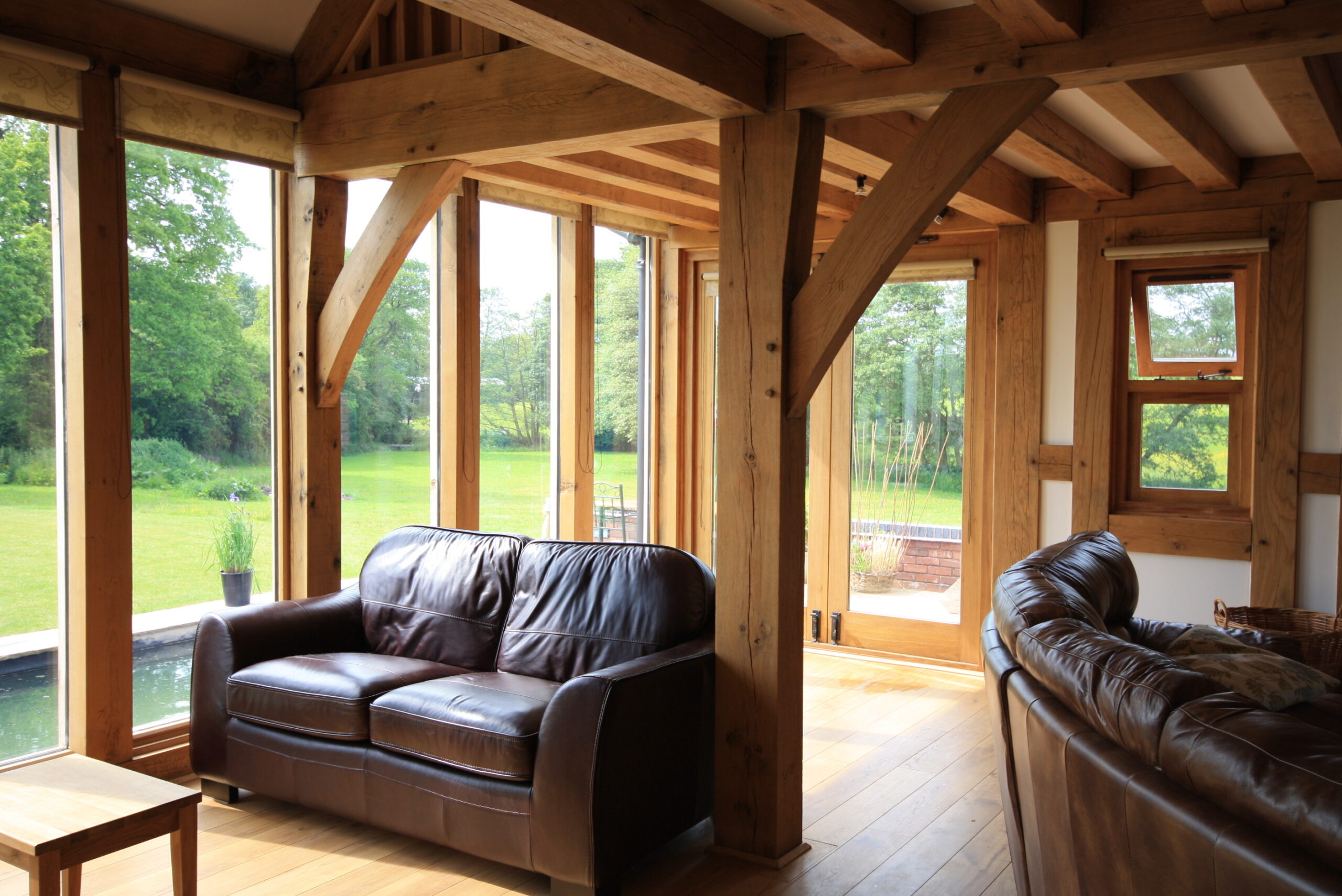 Exposed oak frame in living area with full height glazing looking out onto the garden
