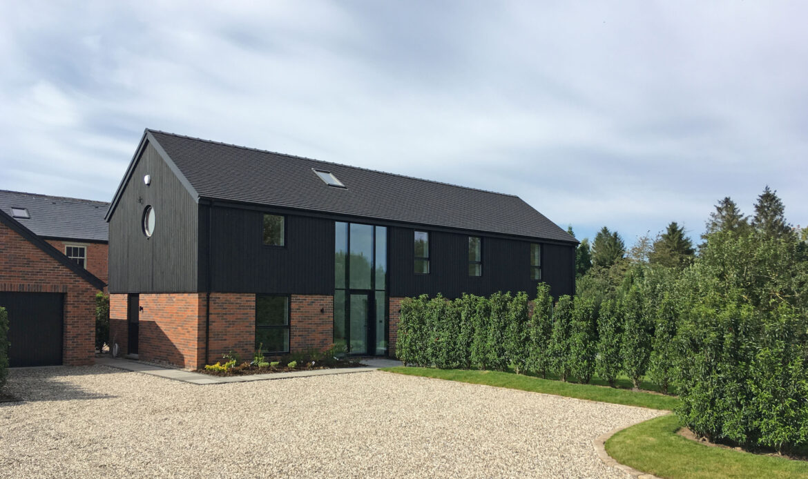 timber and brick replacement dwelling in the style of a barn conversion with large glazed openings