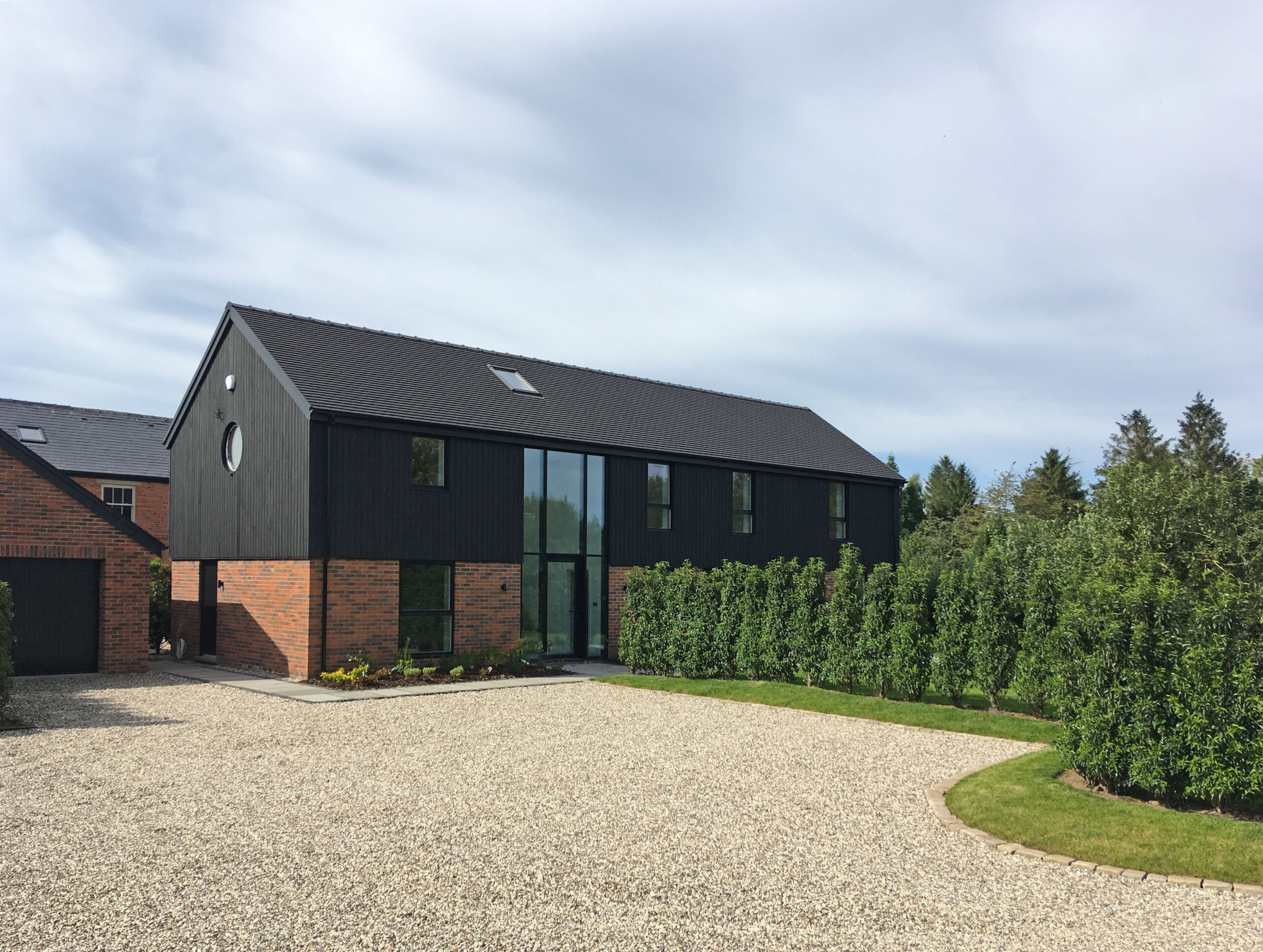timber and brick replacement dwelling in the style of a barn conversion with large glazed openings
