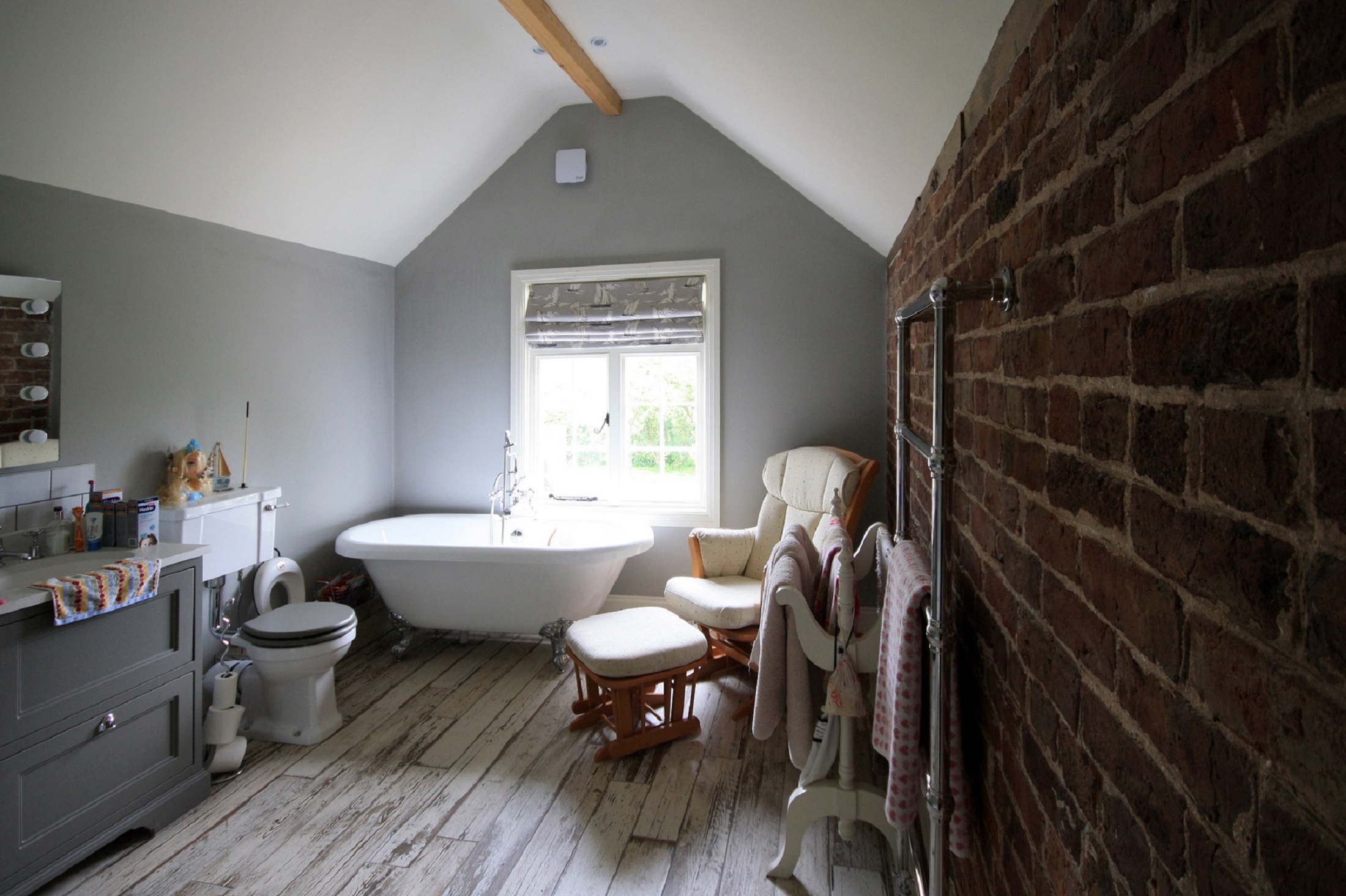 bathroom with exposed brick wall and raked ceiling