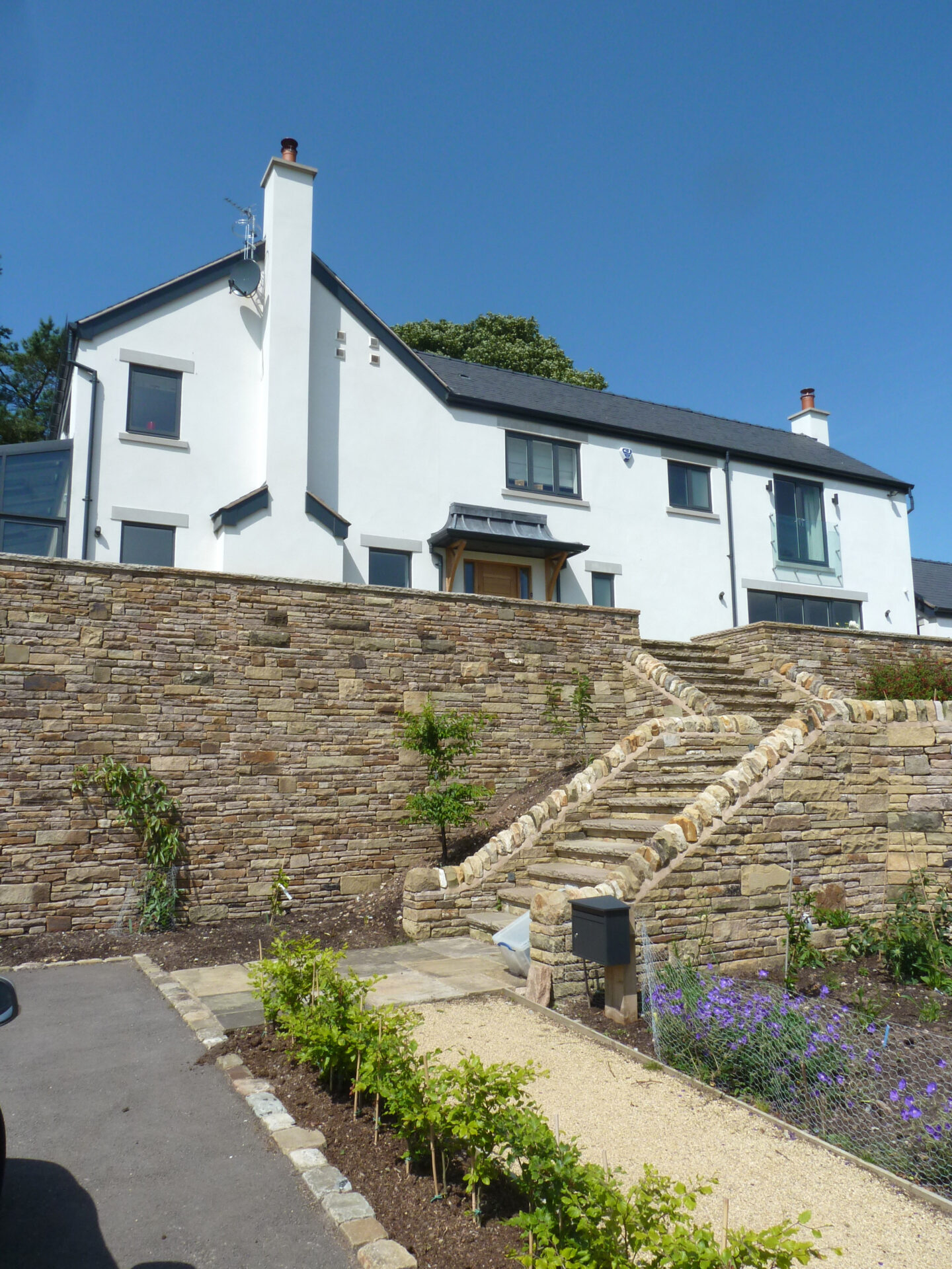 landscaping works emphasising the elevated dwelling with quality stone retaining walls and plants