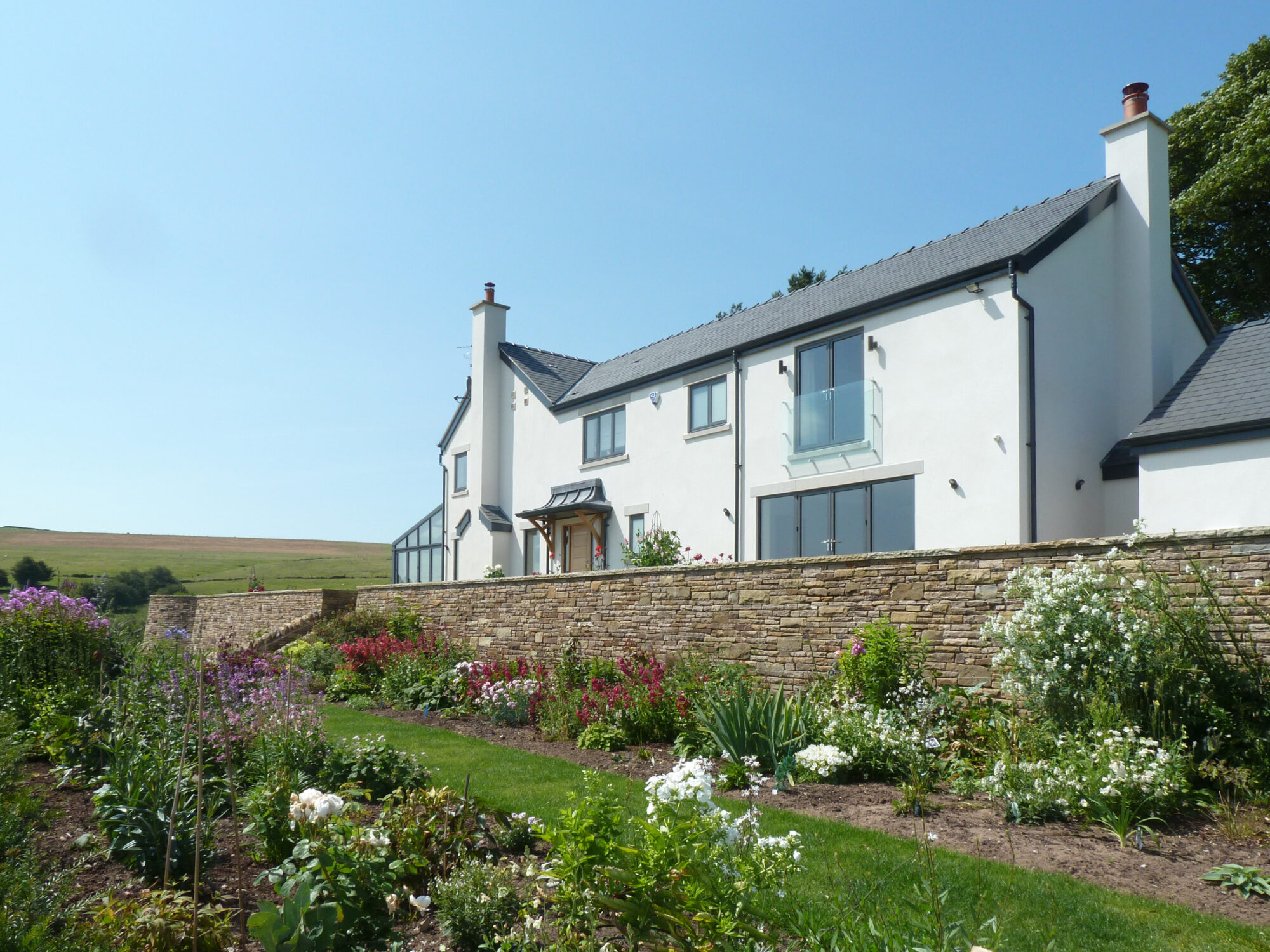 replacement dwelling set in new landscape with stone retaining walls and curated planting