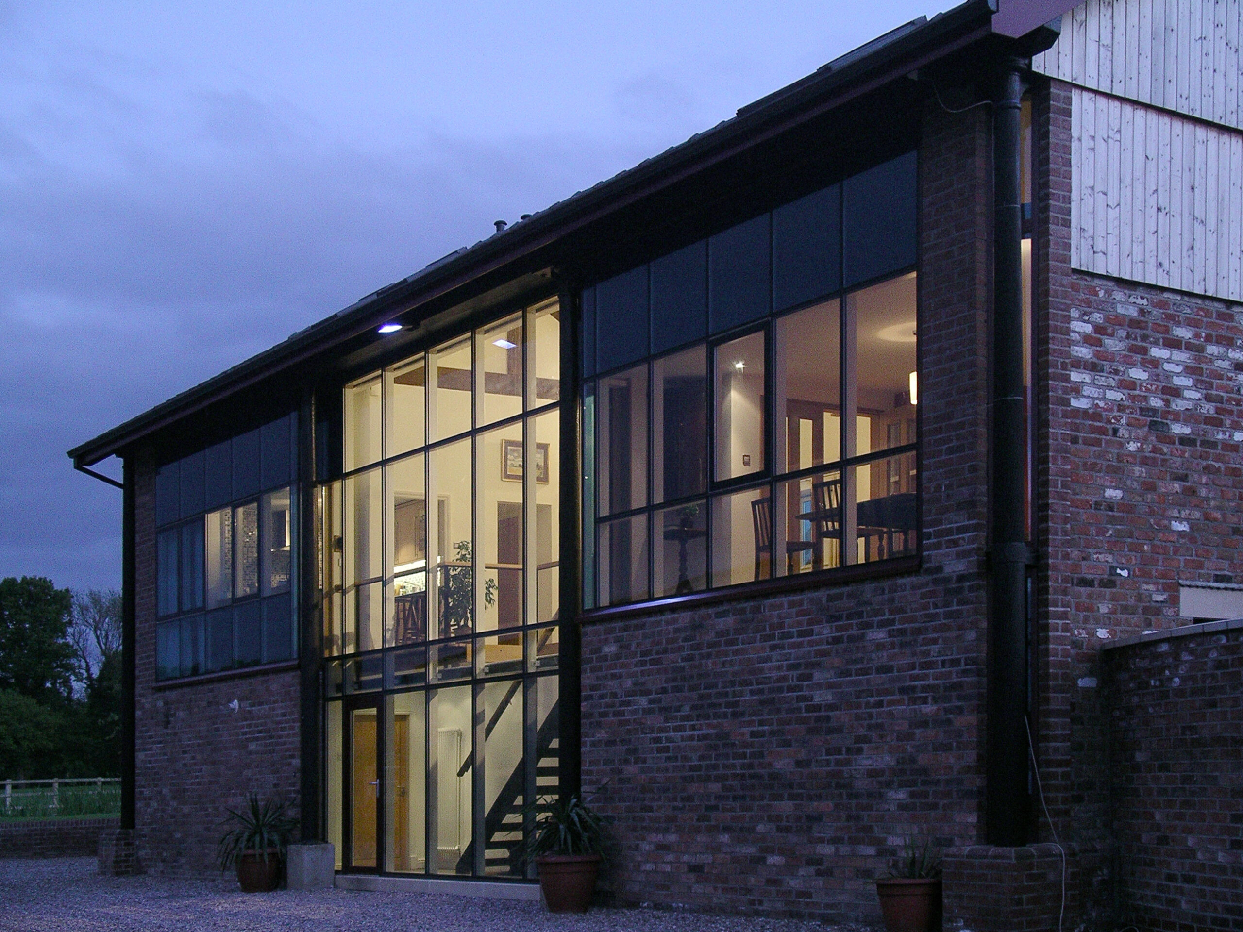 evening image of barn conversion with timber cladding and large glazed openings