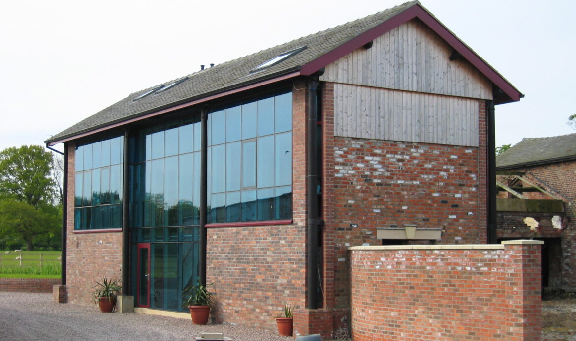 brick barn conversion with timber cladding, large glazed openings and steel columns