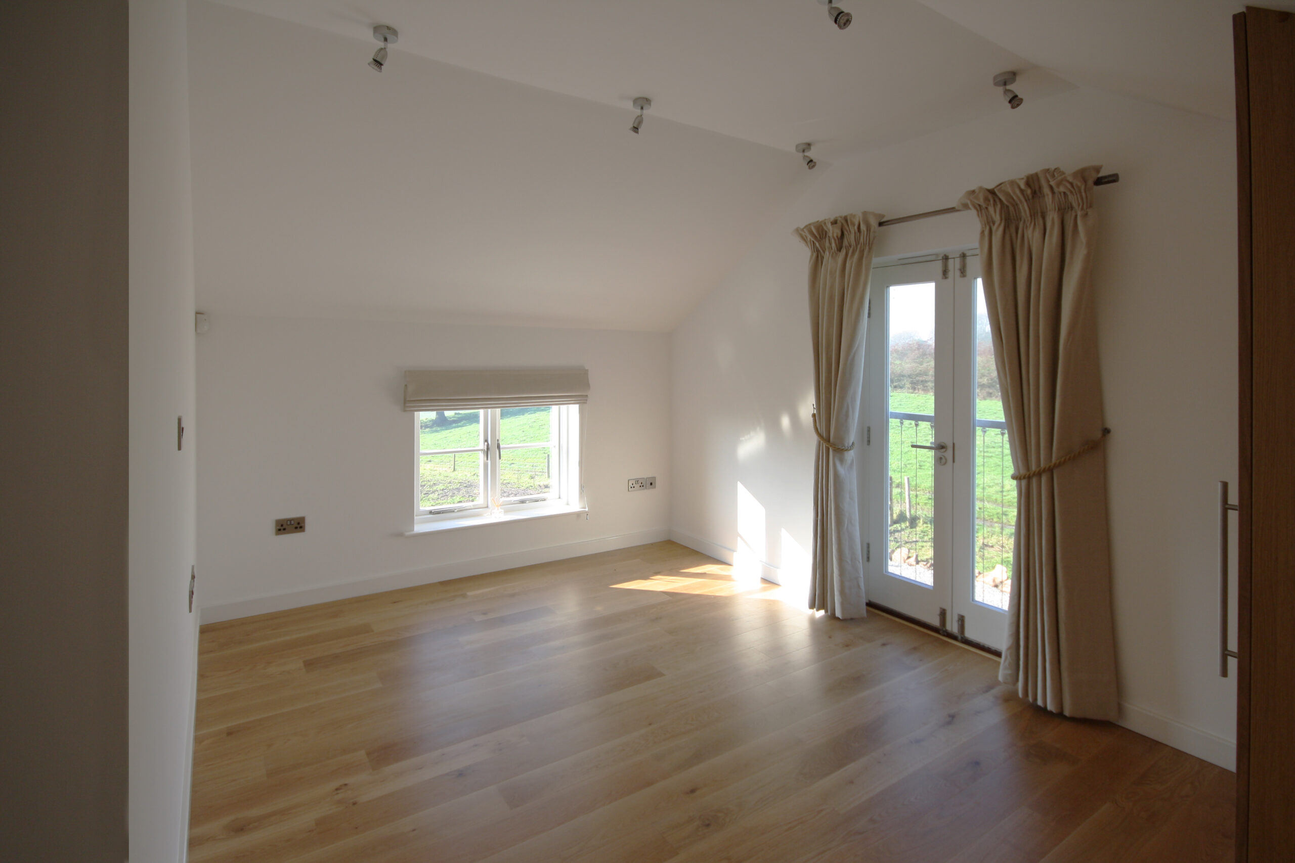 first floor bedroom with raked ceiling and juliet balcony