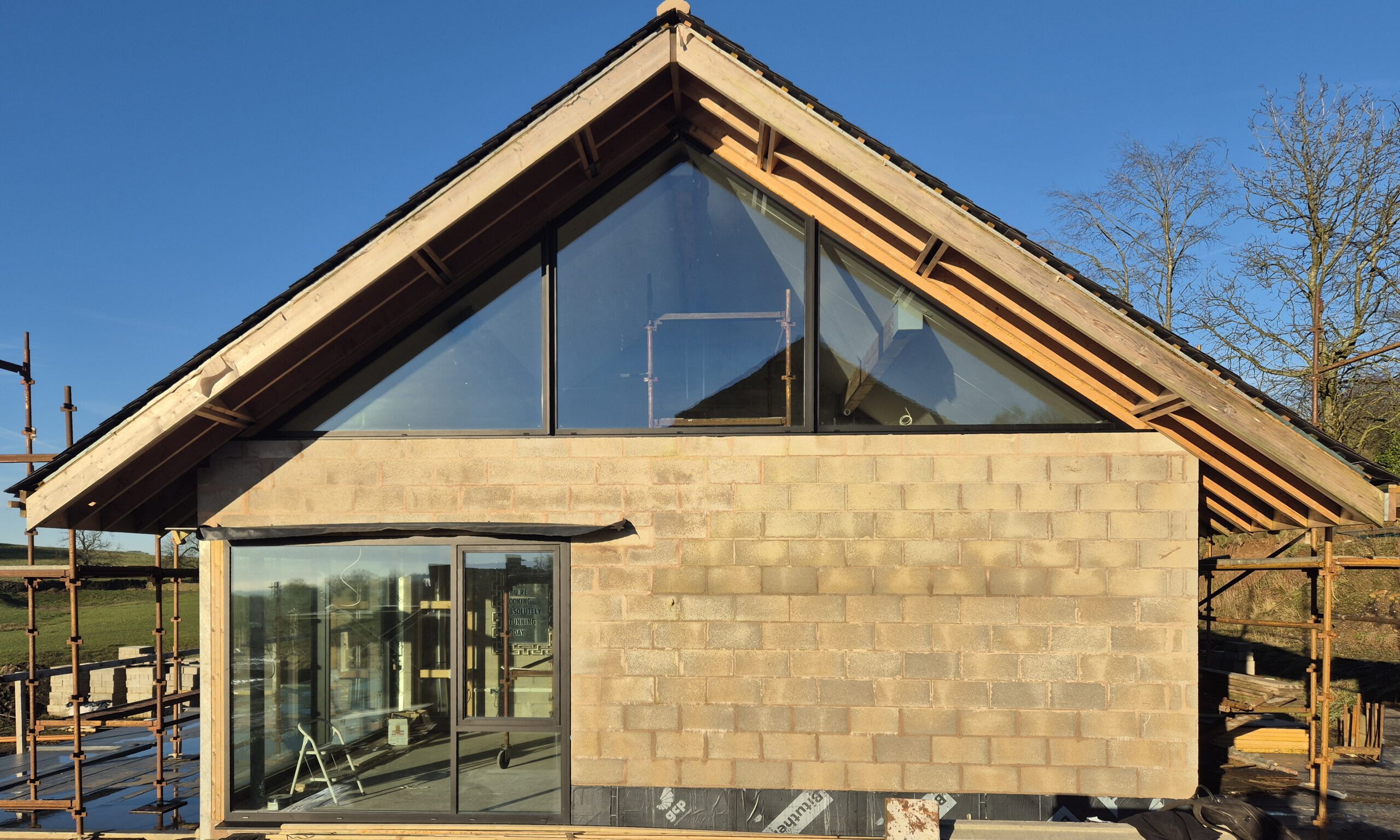 replacement dwelling at Slidemoor under construction with large glazed areas and overhanging roof