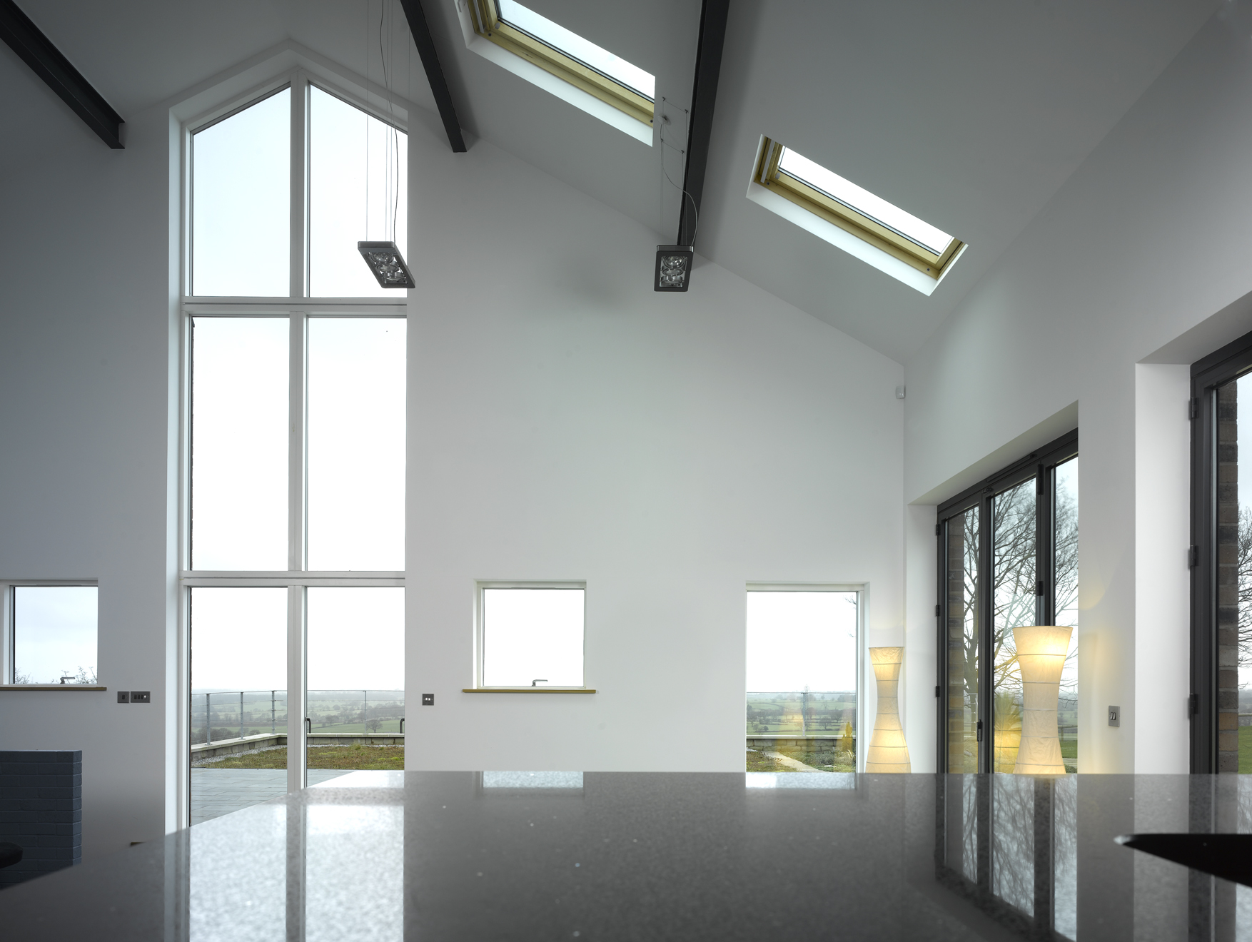 double height living space with raked ceiling and floor to ceiling glazing and rooflights
