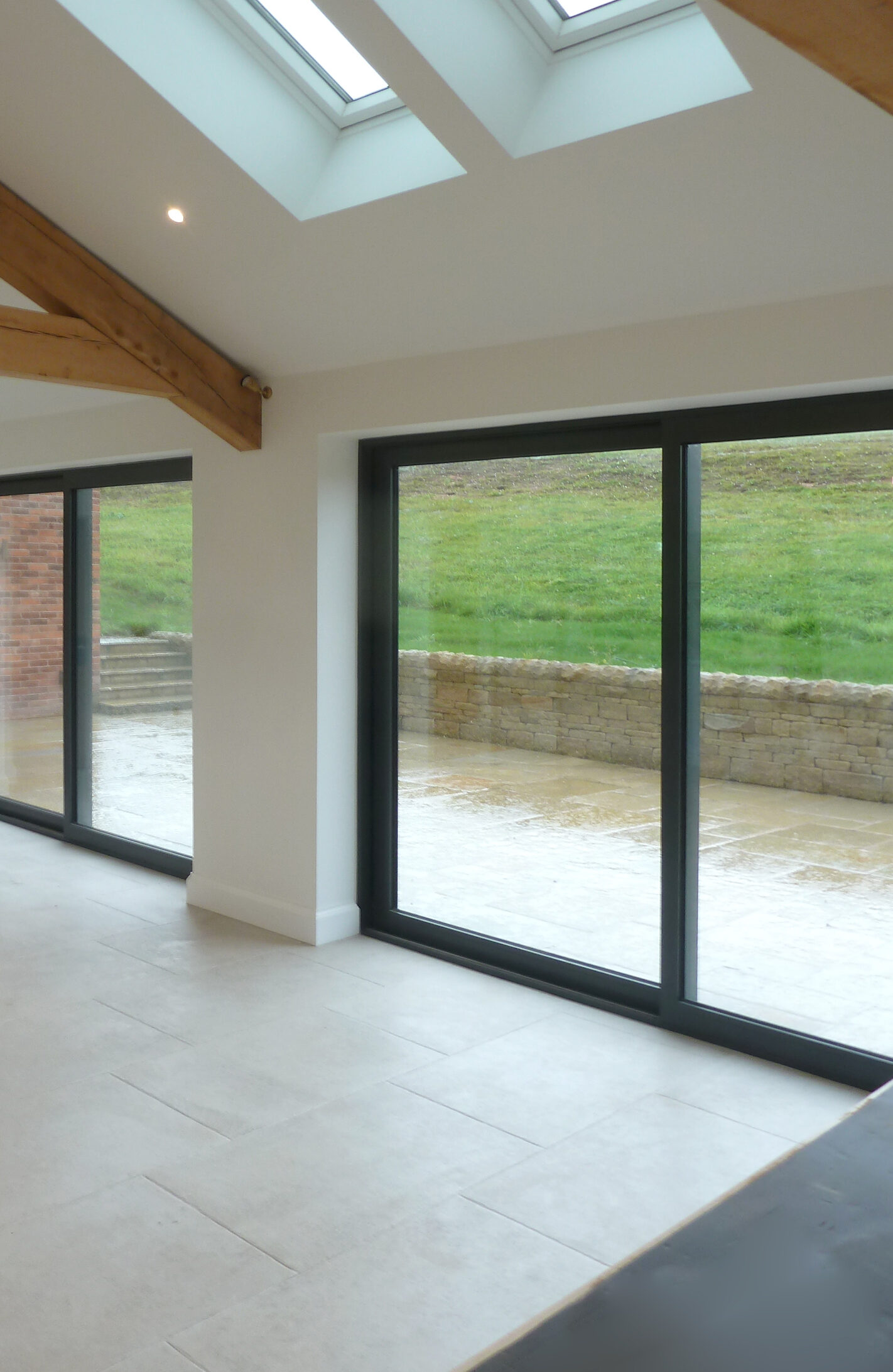 sliding doors opening to rear patio area off the dining and living area with rooflights and exposed timber roof structure