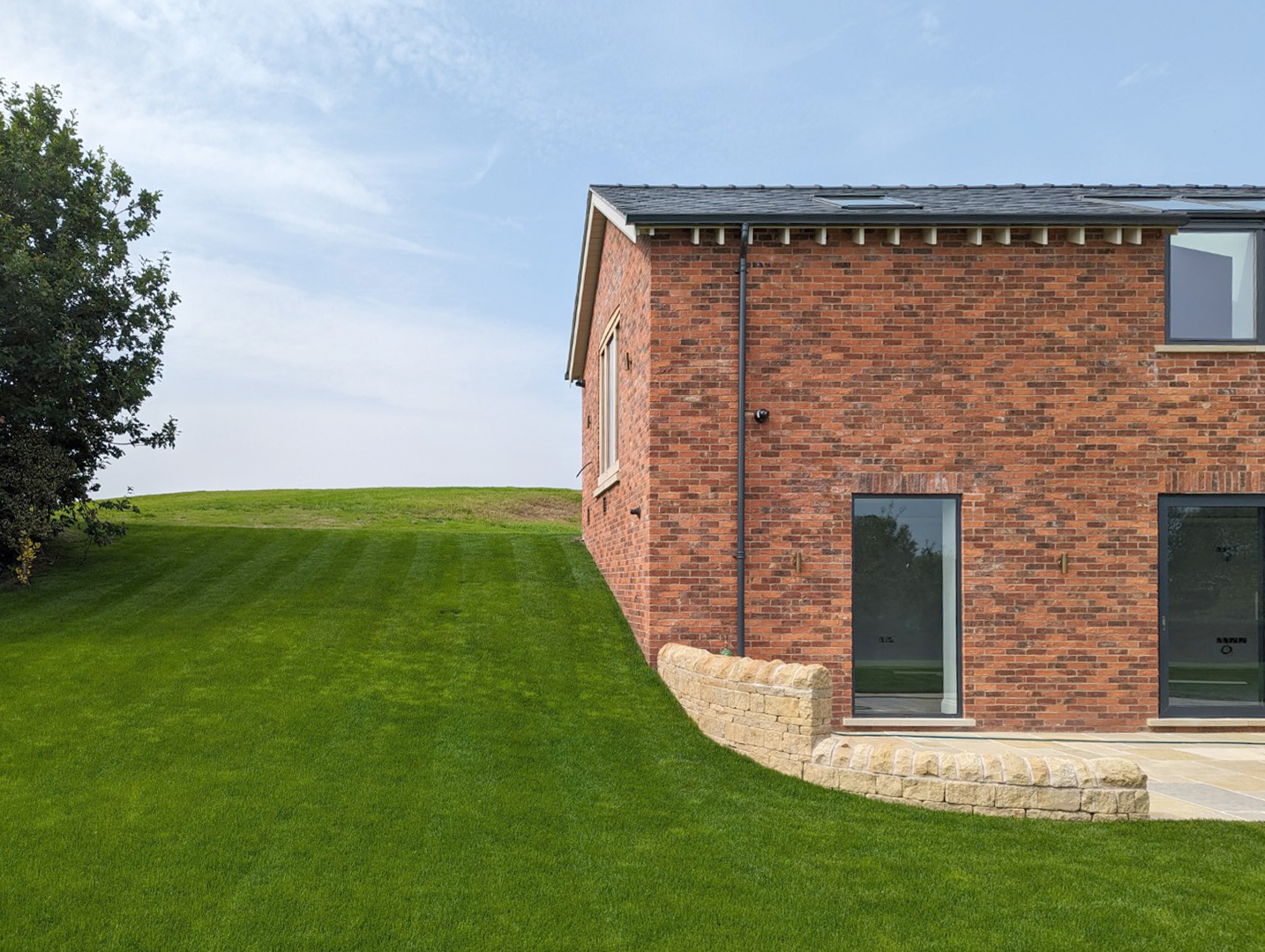 Brick ancillary building with banked land to the site with rear and site retaining walls