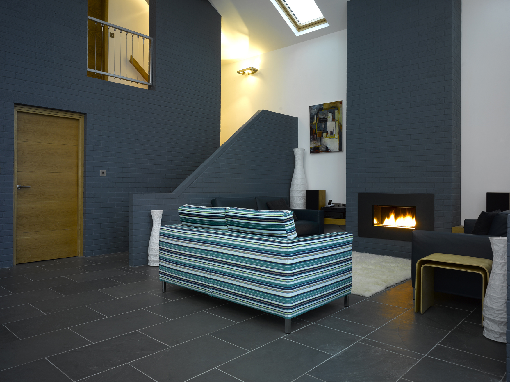 Open plan living space with open staircase and exposed brick chimney and rooflights