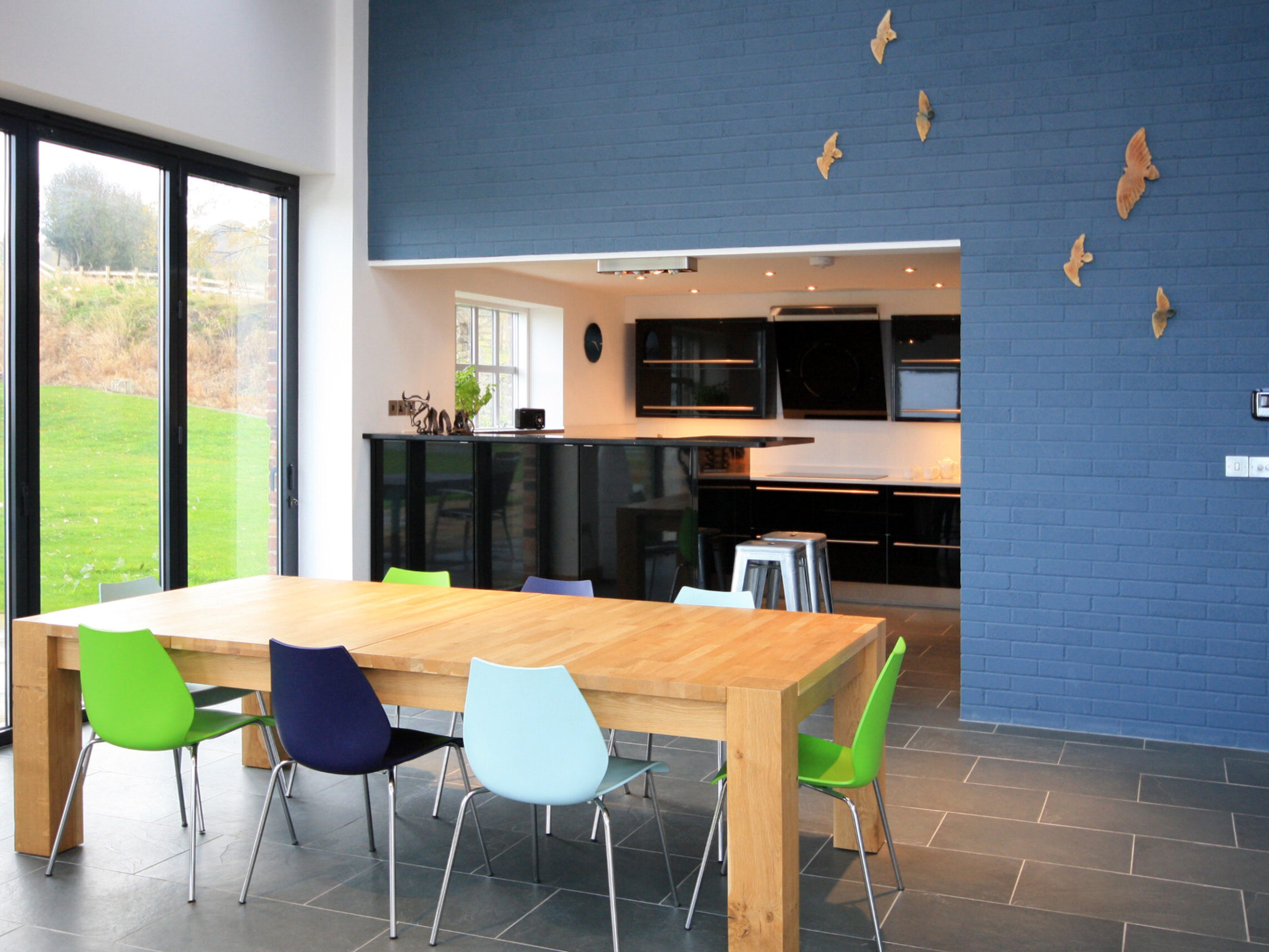 open kitchen with bar/serving area opening onto dining area with large glazed doors offering views into the private gardens
