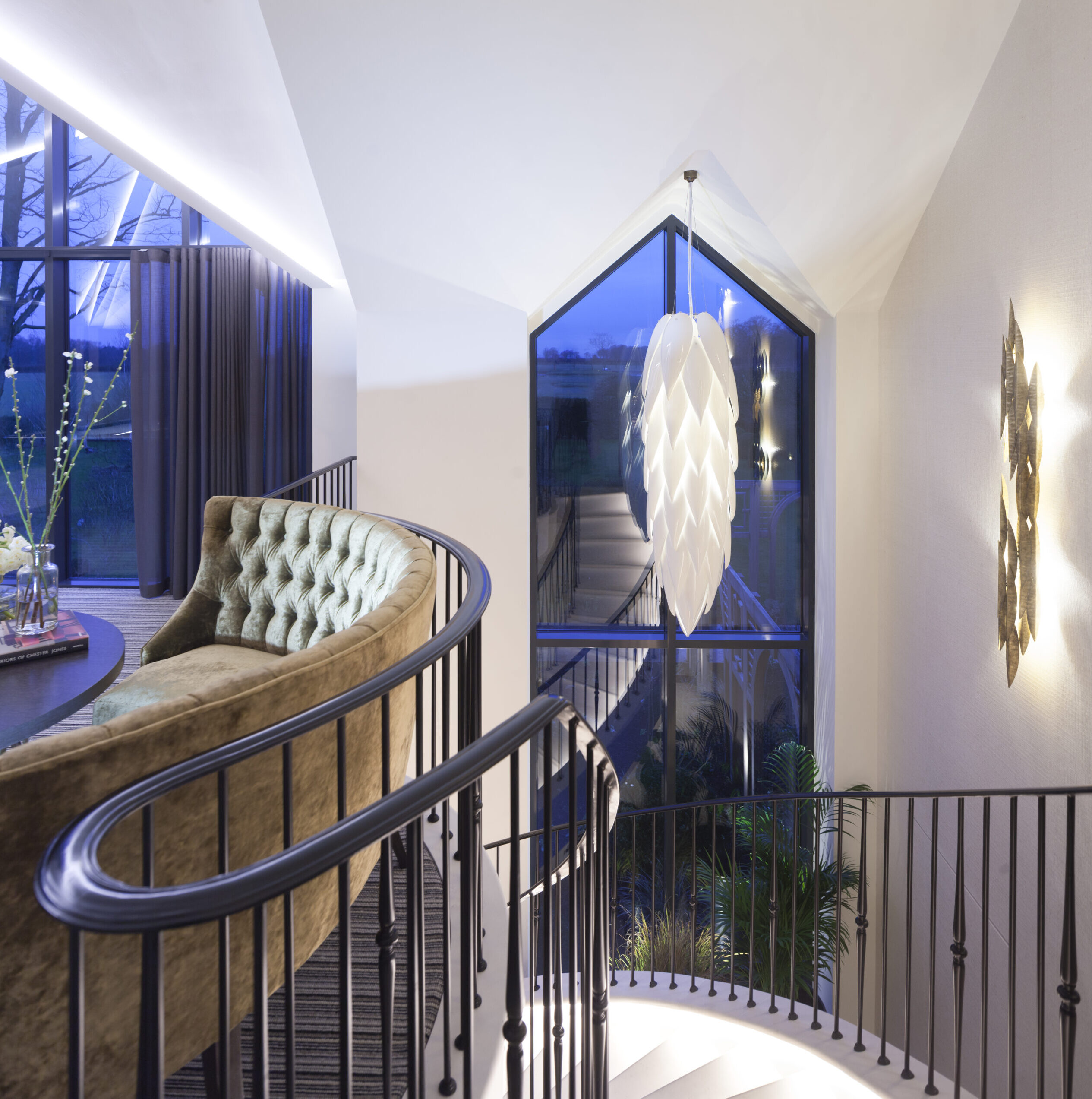 feature lighting above staircase with double height gable end glazing offering views out to surrounding gardens
