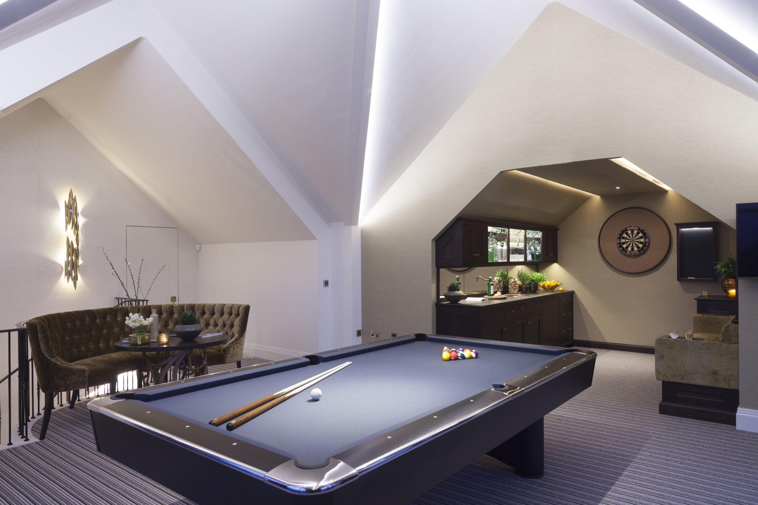 pool table in games room at Ash House with darts board and bar area behind