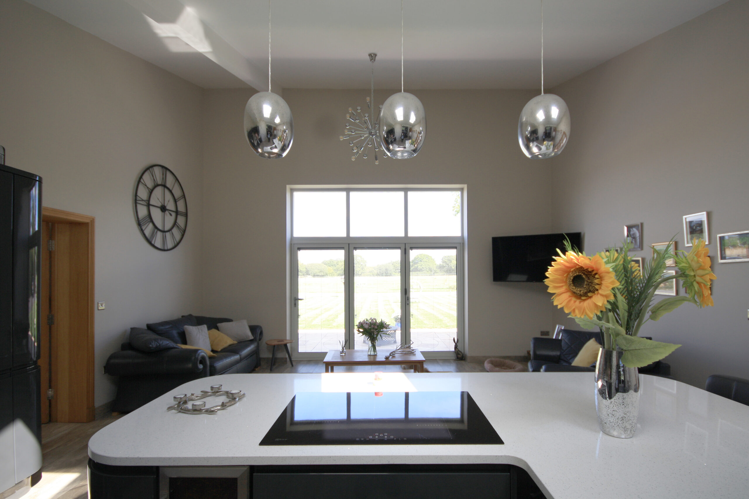 kitchen and sitting area in partial conversion of barn with three pendant lights over the island