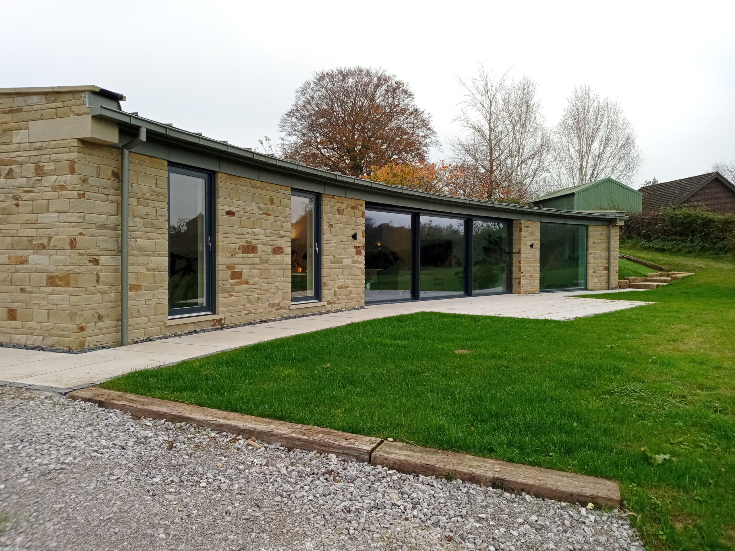 curved stone wall elevation with full height glazing and overhanging roof