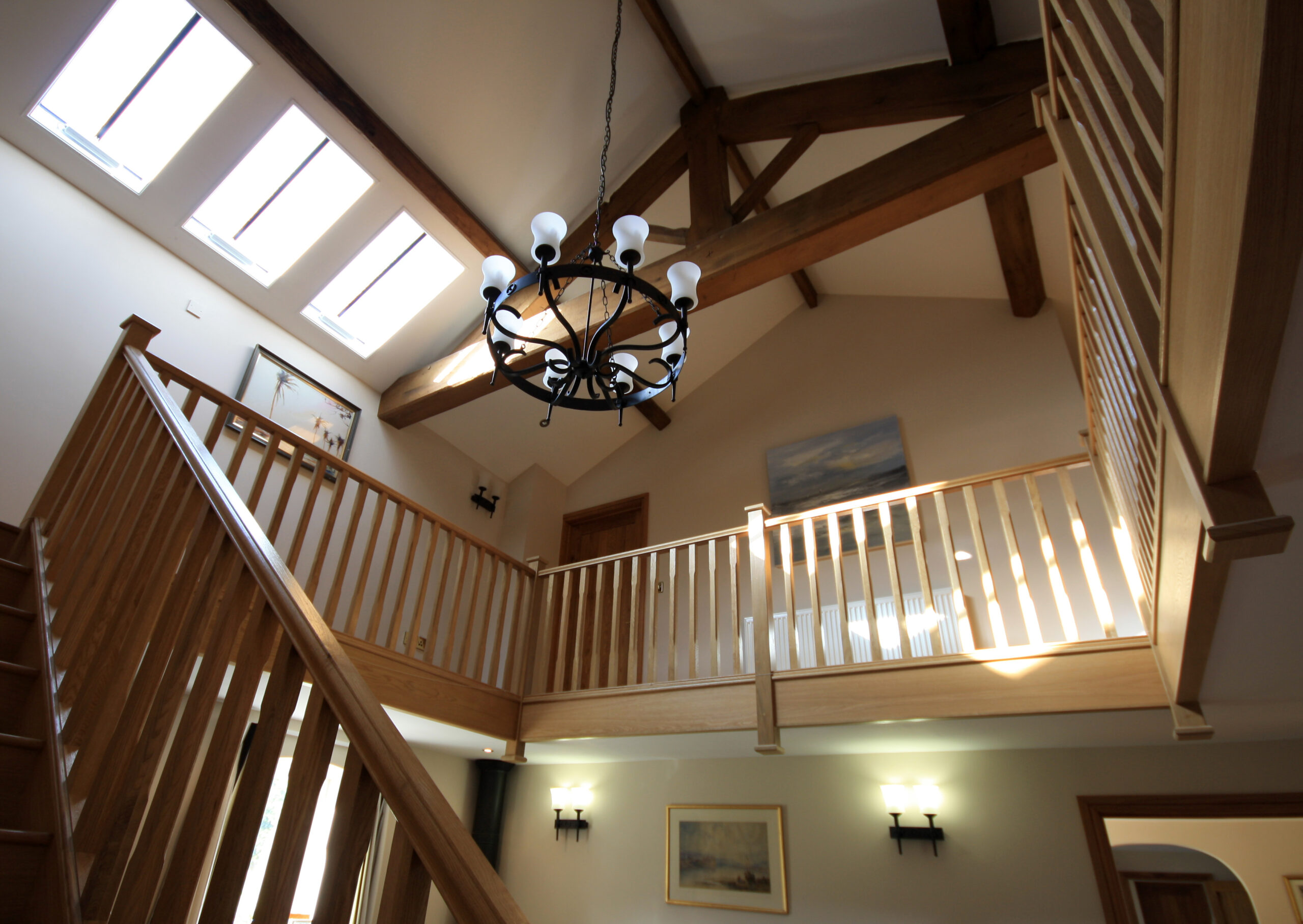 Converted barn with large open entrance hall and galleried landing with statement lighting and exposed timber roof truss and purlins