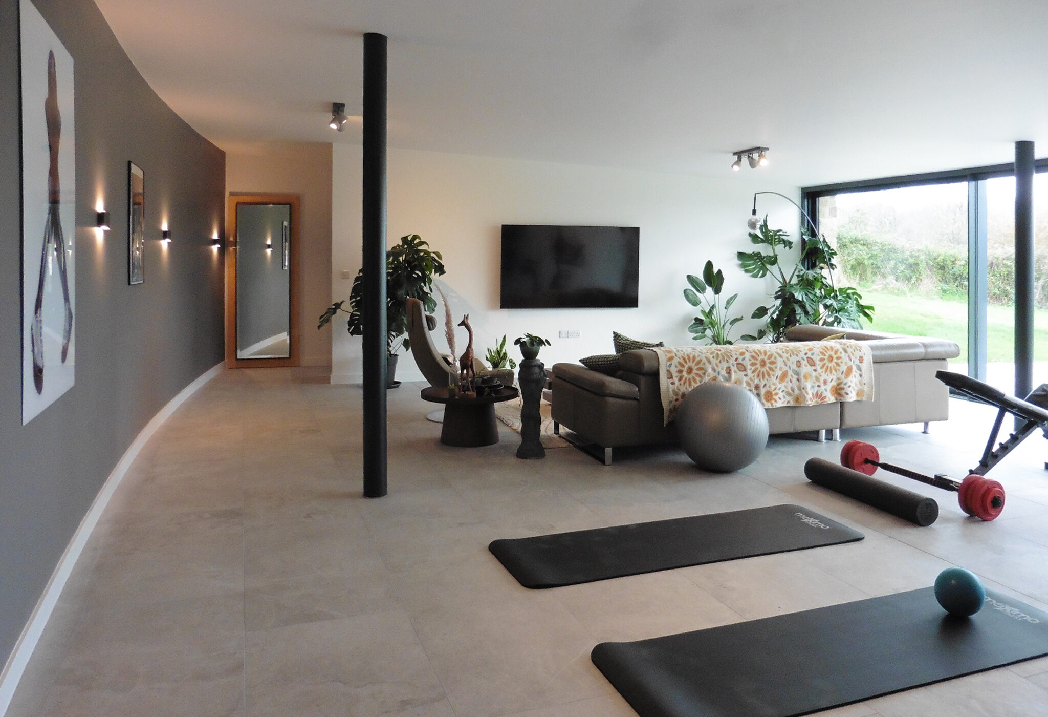 leisure suite with gym equipment, entertaining area and sofa with large glazing looking onto the countryside and Bosley Cloud