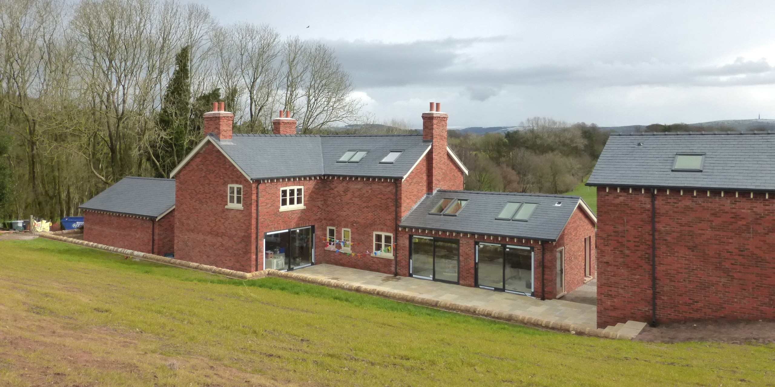 Hazelwall Cottage rear elevation view from top of bank down to Hazelwall Cottage with large opening to open plan living space and sitting room