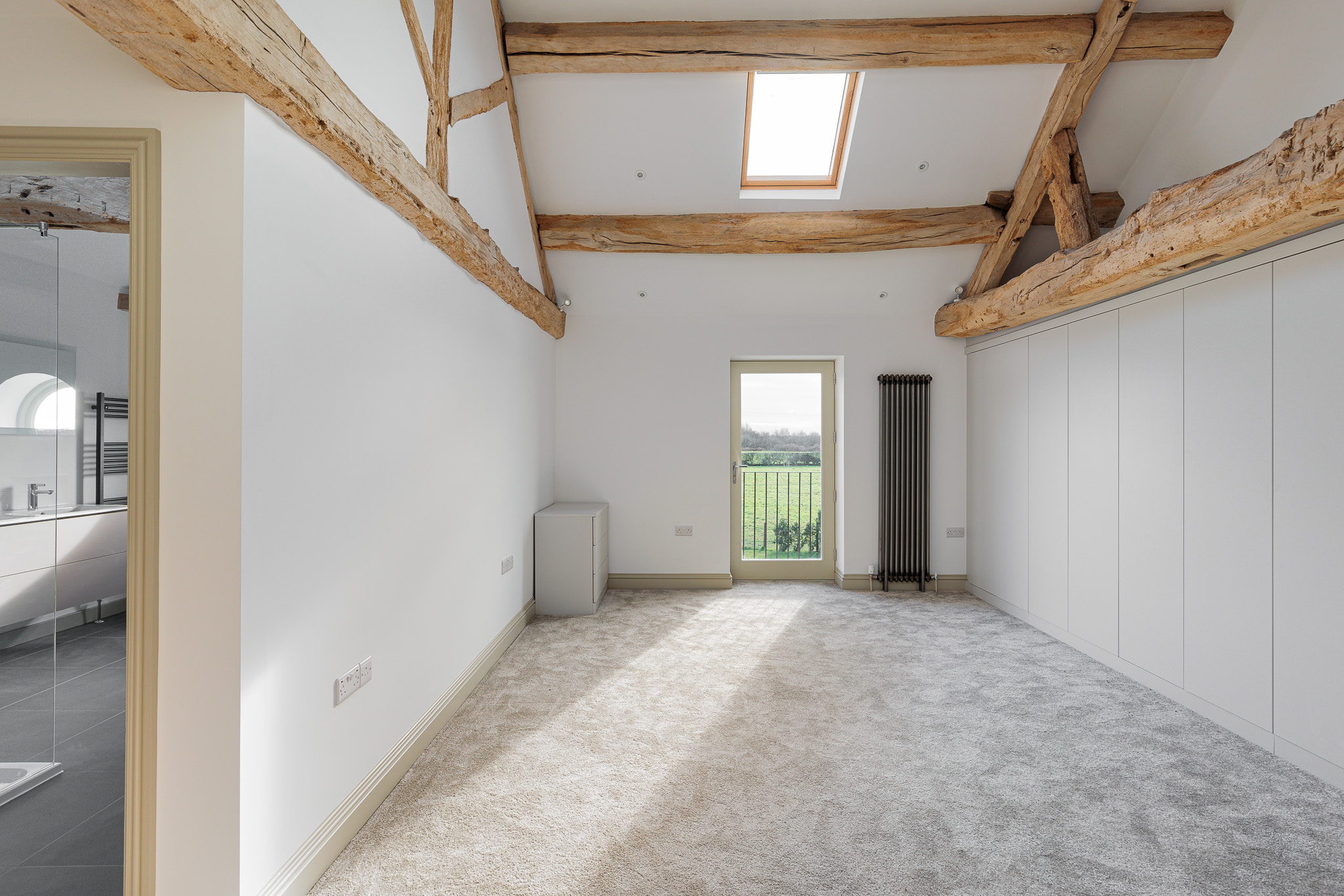 First floor bedroom with juliet balcony and built in wardrobes. Exposed retained aok roof trusses and purlins with new rooflight