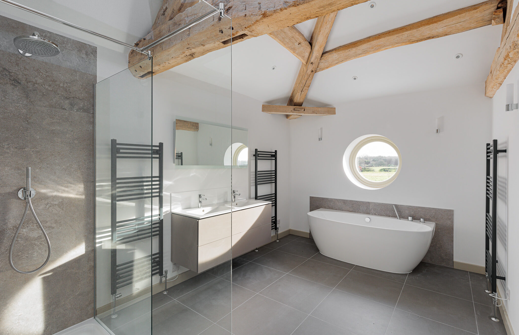 bathroom with exposed retained oak roof structure with original circular opening retained over bath