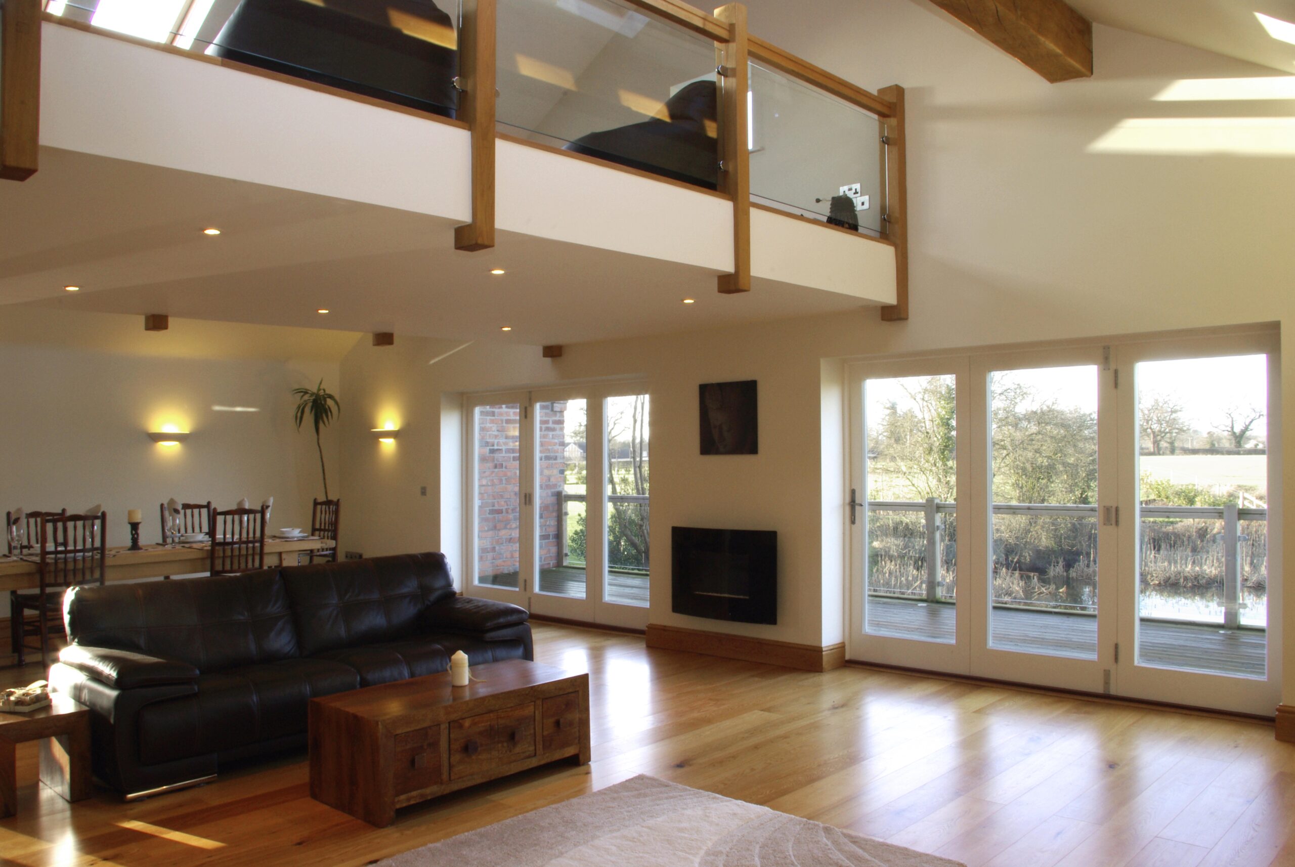 Open plan litchen/dining/living space at Poole Farm with mezzanine floor over with seating and external decking with views to surrounding fields