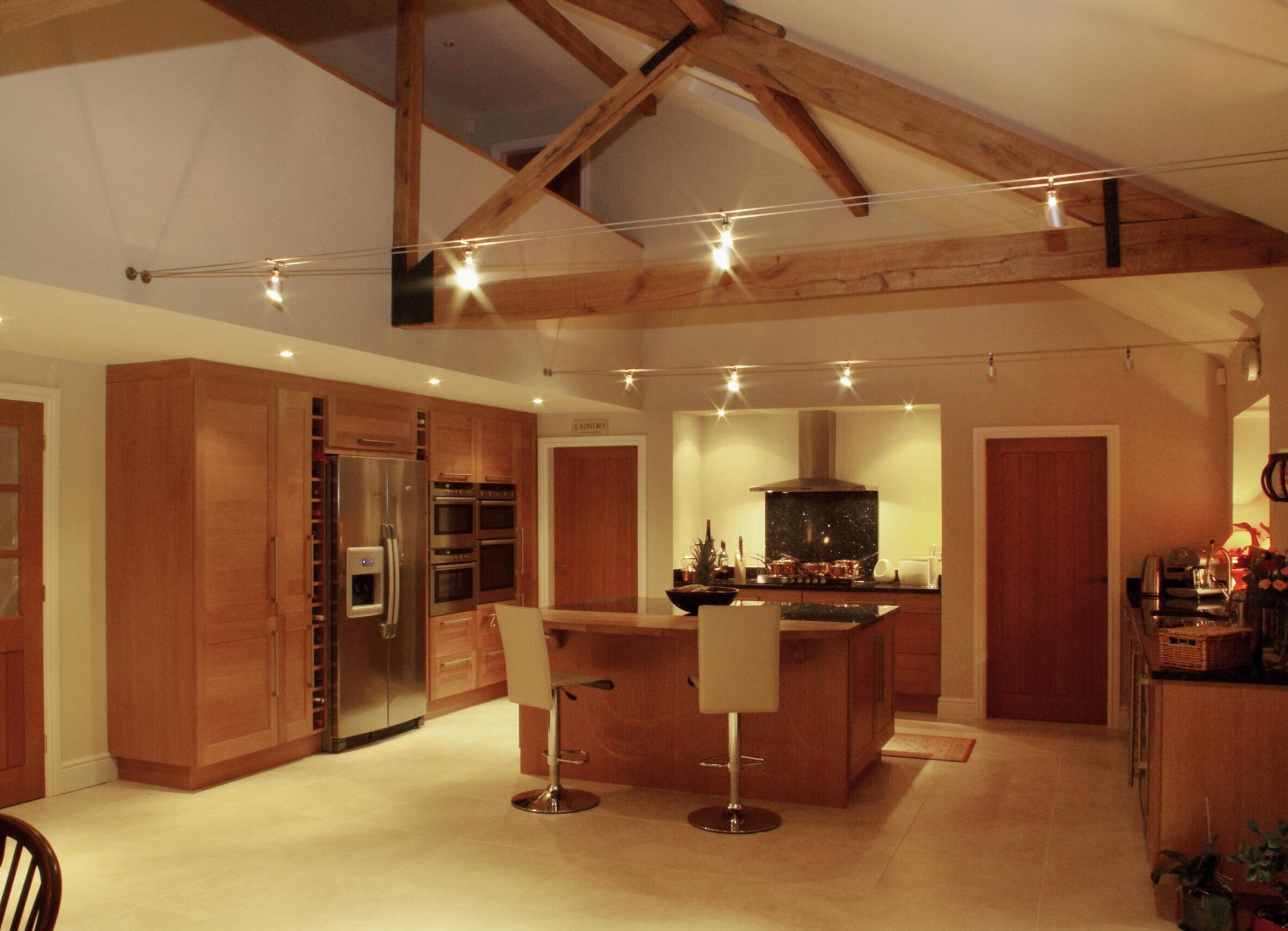 open plan kitchen area with exposed timber roof trusses and mezzanine floor above