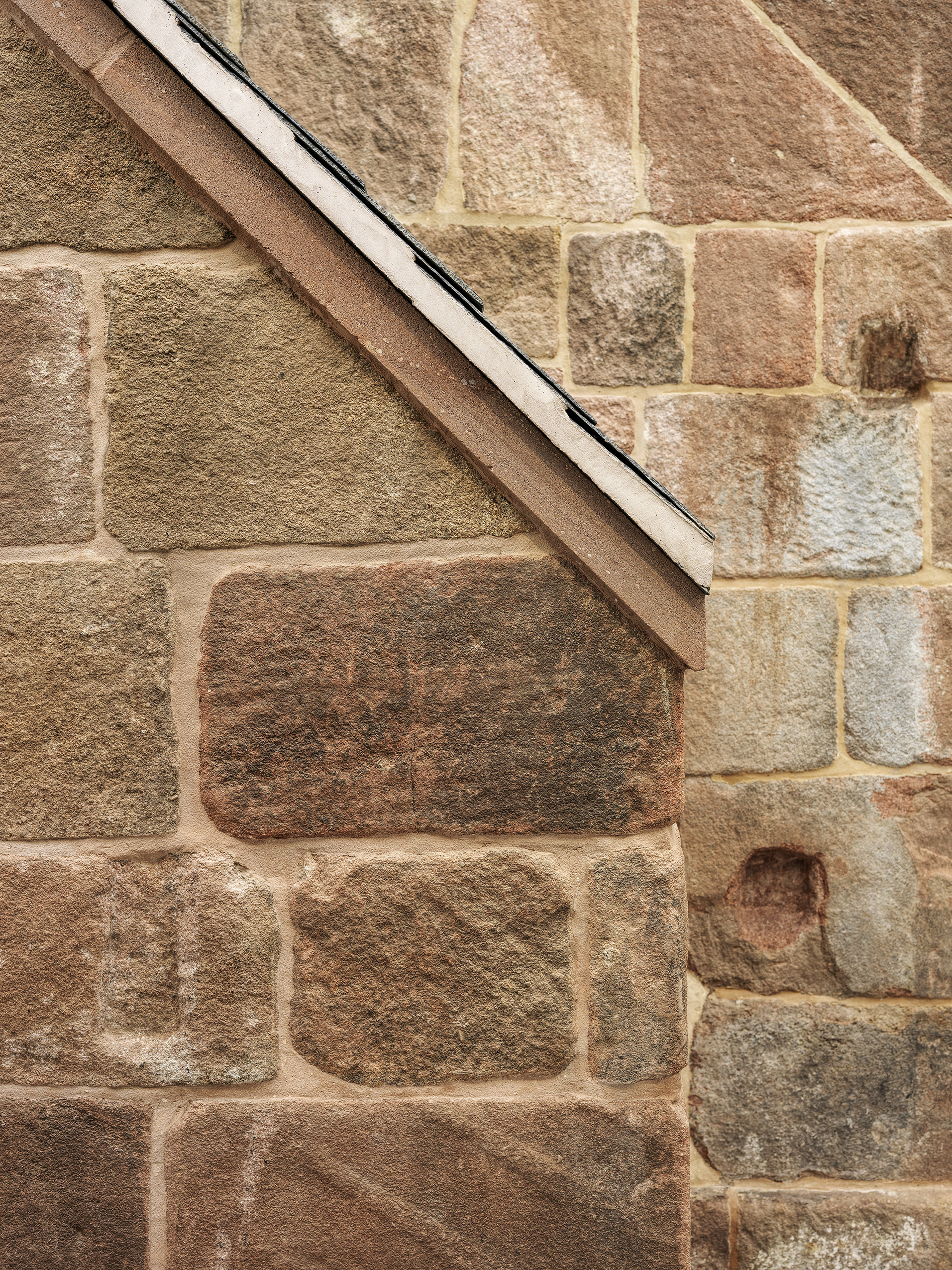 Detail of a tiled finish on an exposed stone chimney