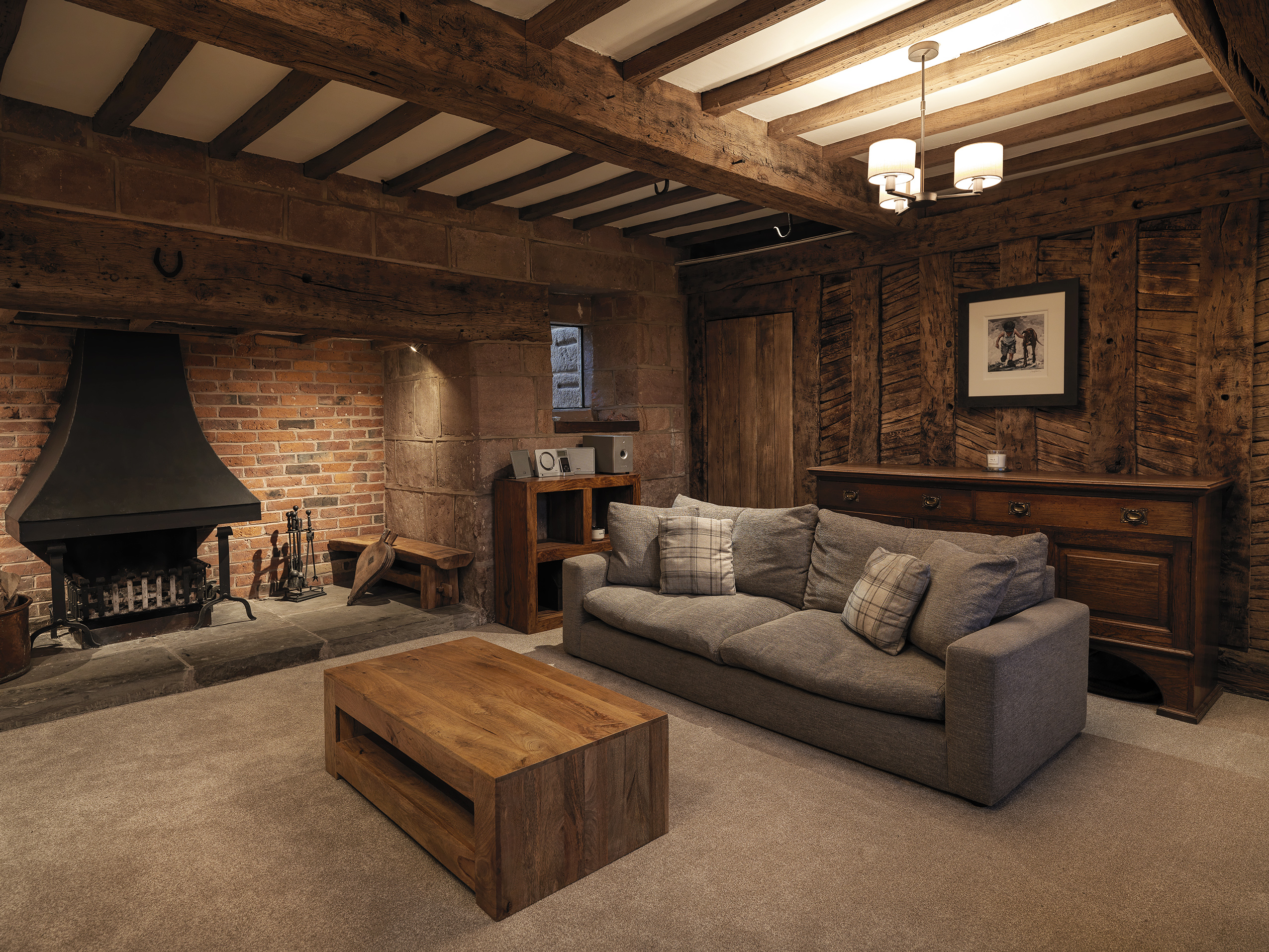 A renovated living room to a Grade 2 listed farmhouse with the original fireplace and timber walls opened up. With exposed timber beams and ceiling joists.