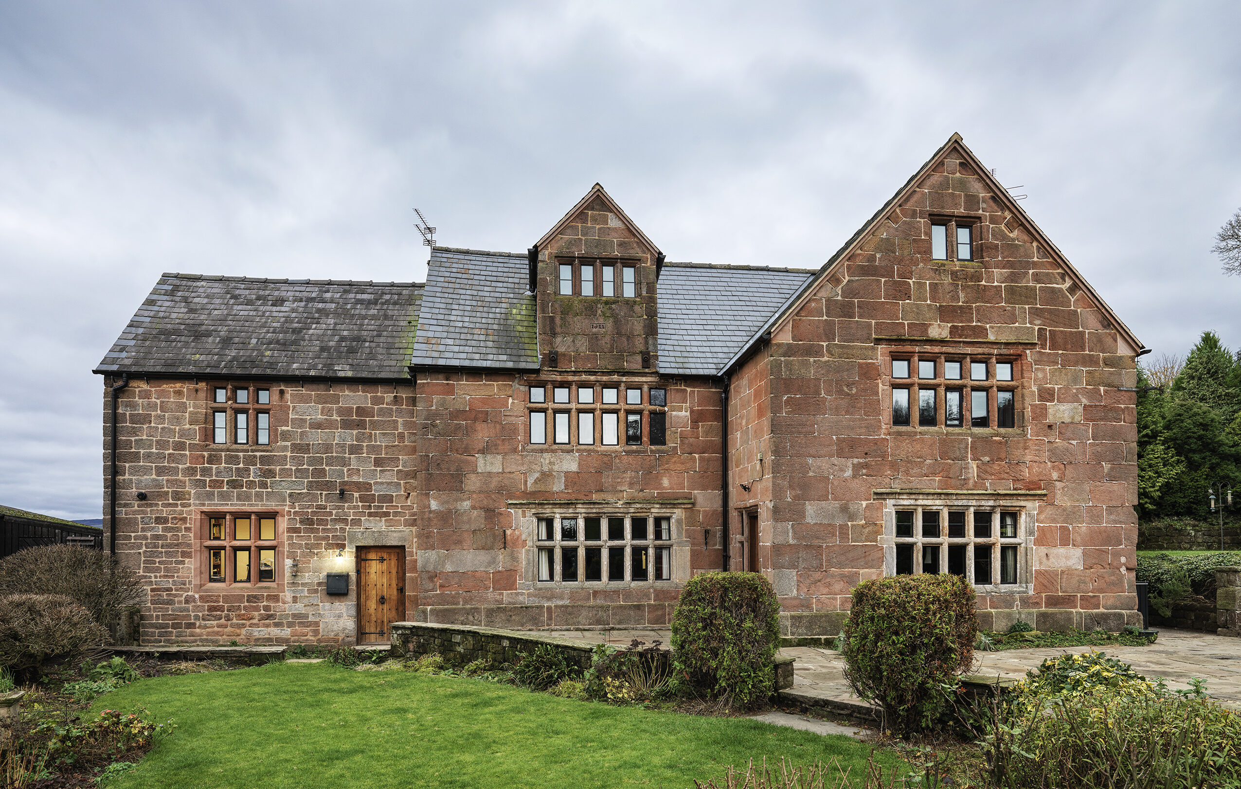 renovated front elevation of a Grade 2 listed farmhouse with new glazing installed to mullion framed windows and roof covering, eaves and verge details renovated to complement the style and importance of the house.