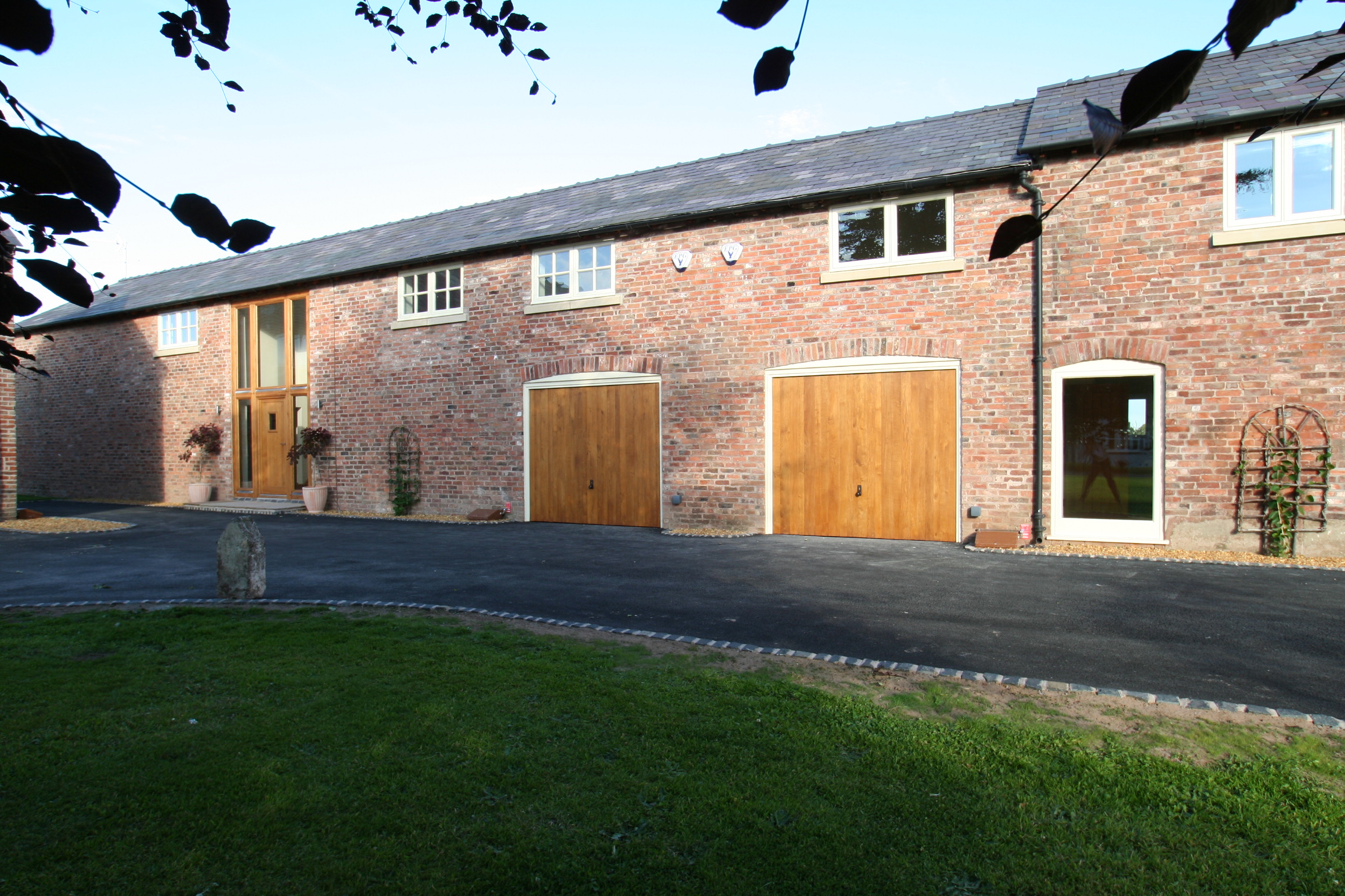 A front elevation to one of the converted barns at Poole Farm with large double height opening to the entrance hall and openings retained recalling the buildings previous functions