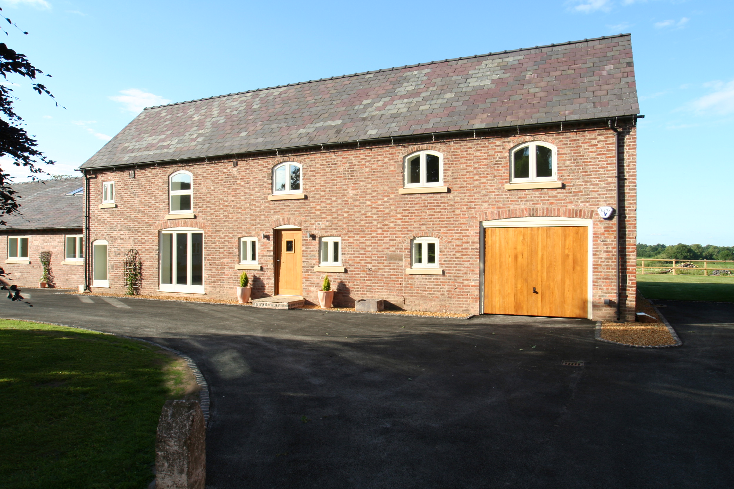 Brick barn conversion at Poole Farm with single garage door openings and original openings retained