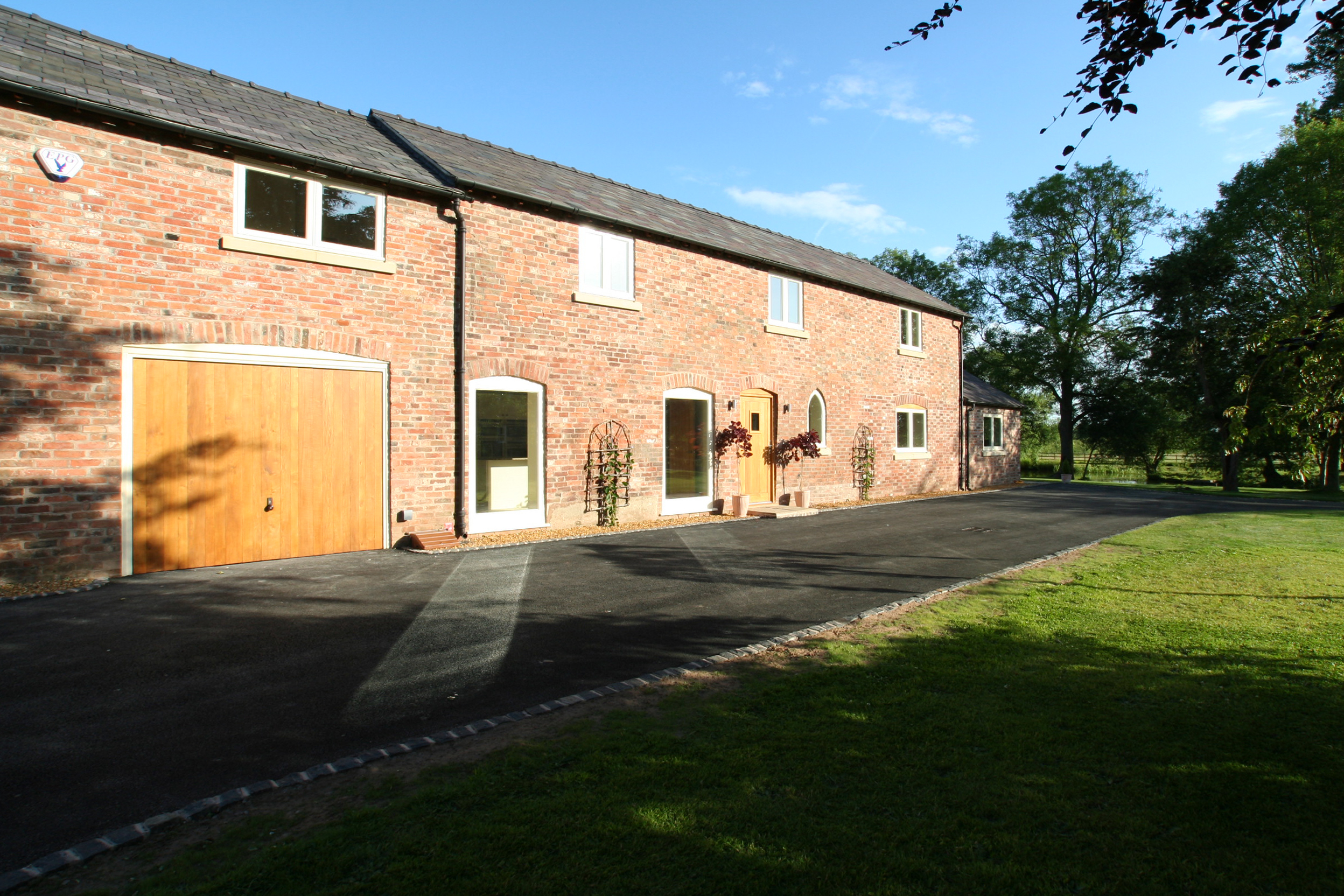 converted brick barn with garages, retained openings and landscaped site