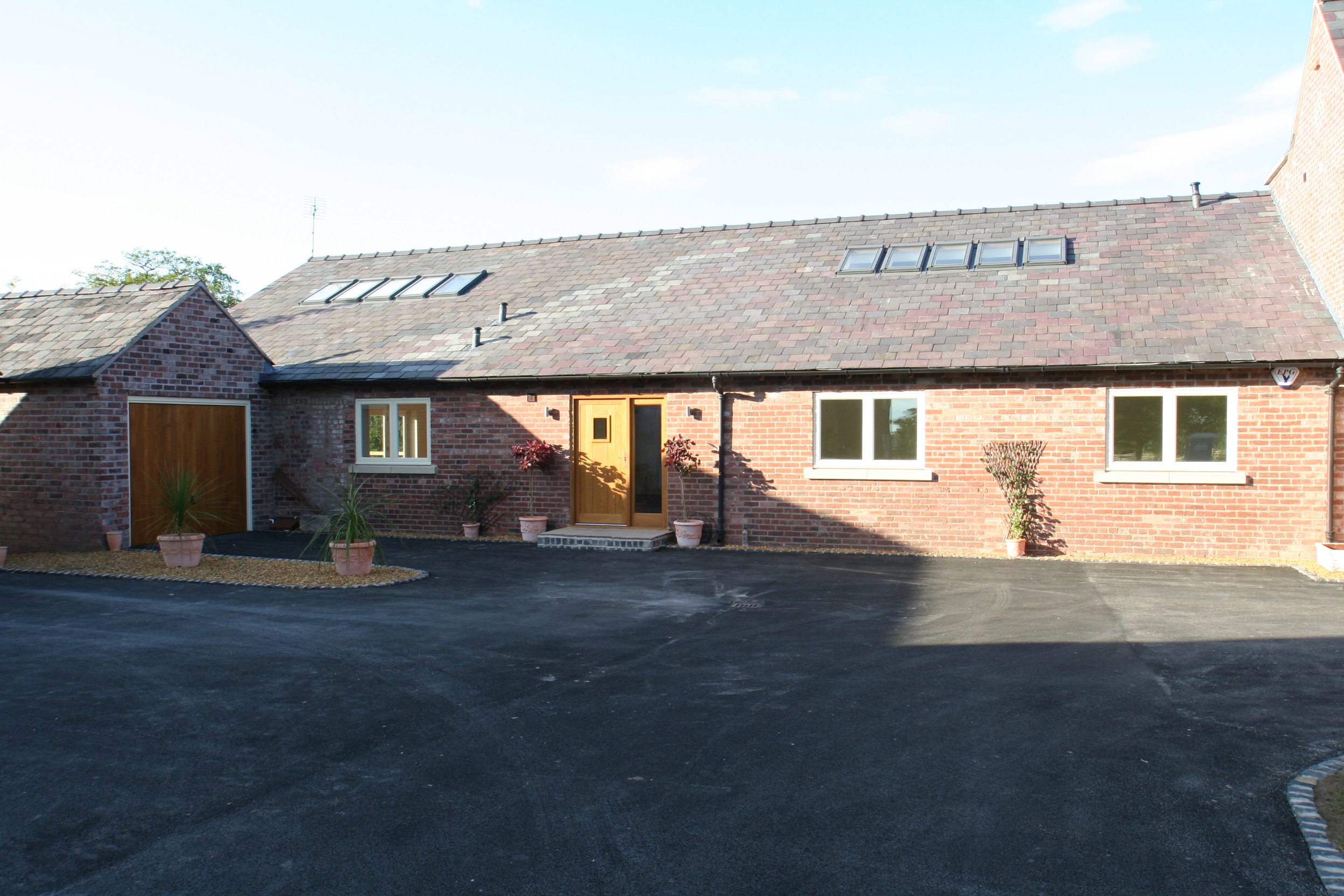 single storey brick barn conversion at Poole farm with rooflights and garage building.