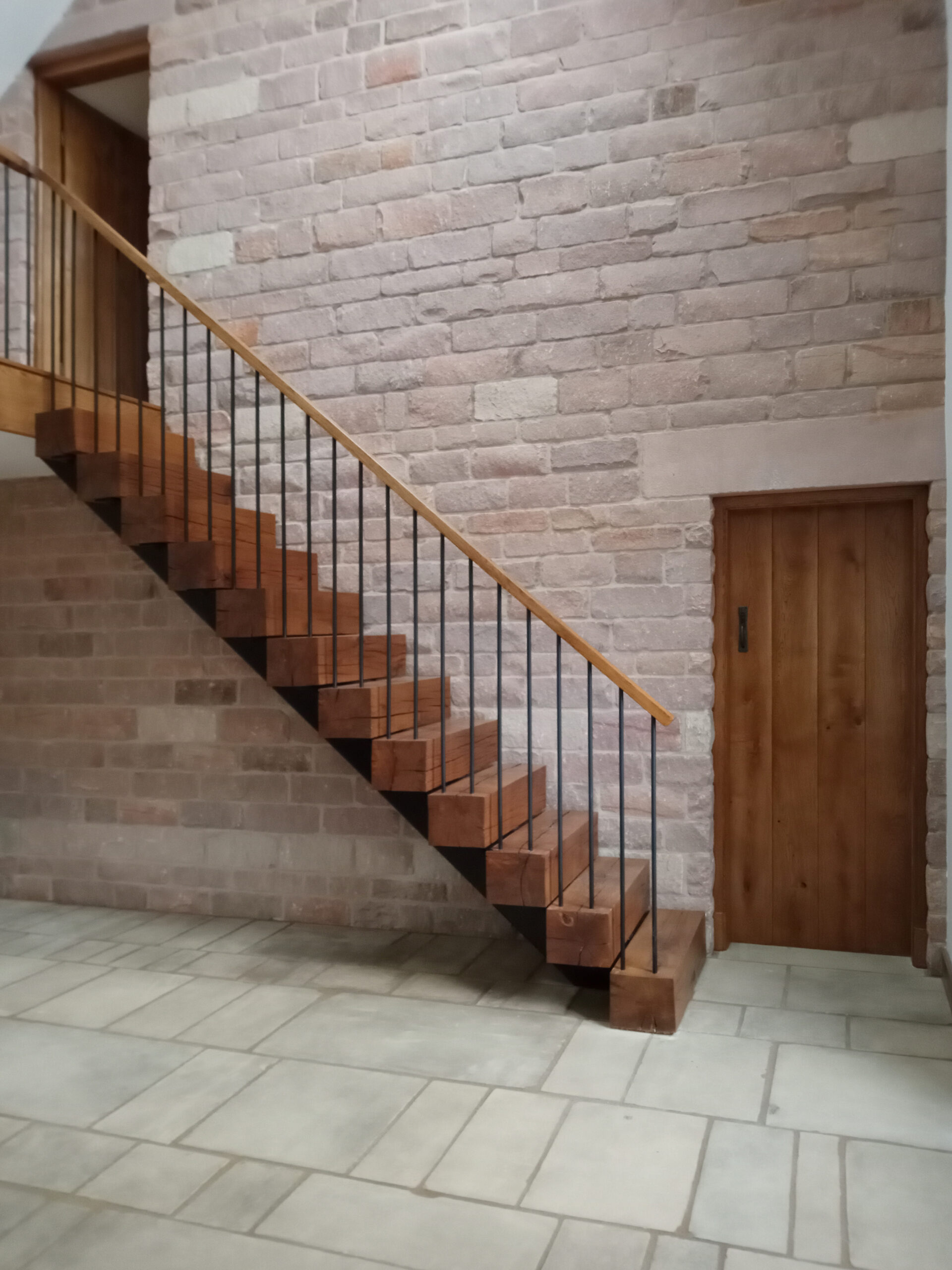 completed staircase at Cloud Wood End Barn with oak treads, steel balustrade and timber handrail set against an exposed stonework internal wall