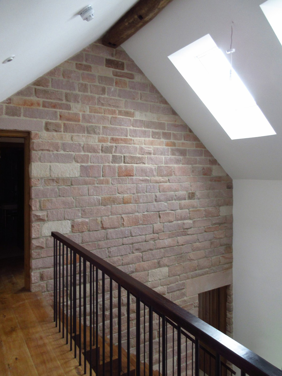 view from first floor landing level at Cloud Wood End Barn with exposed stonework wall internally and retained Oak roof ridge beams and large rooflights