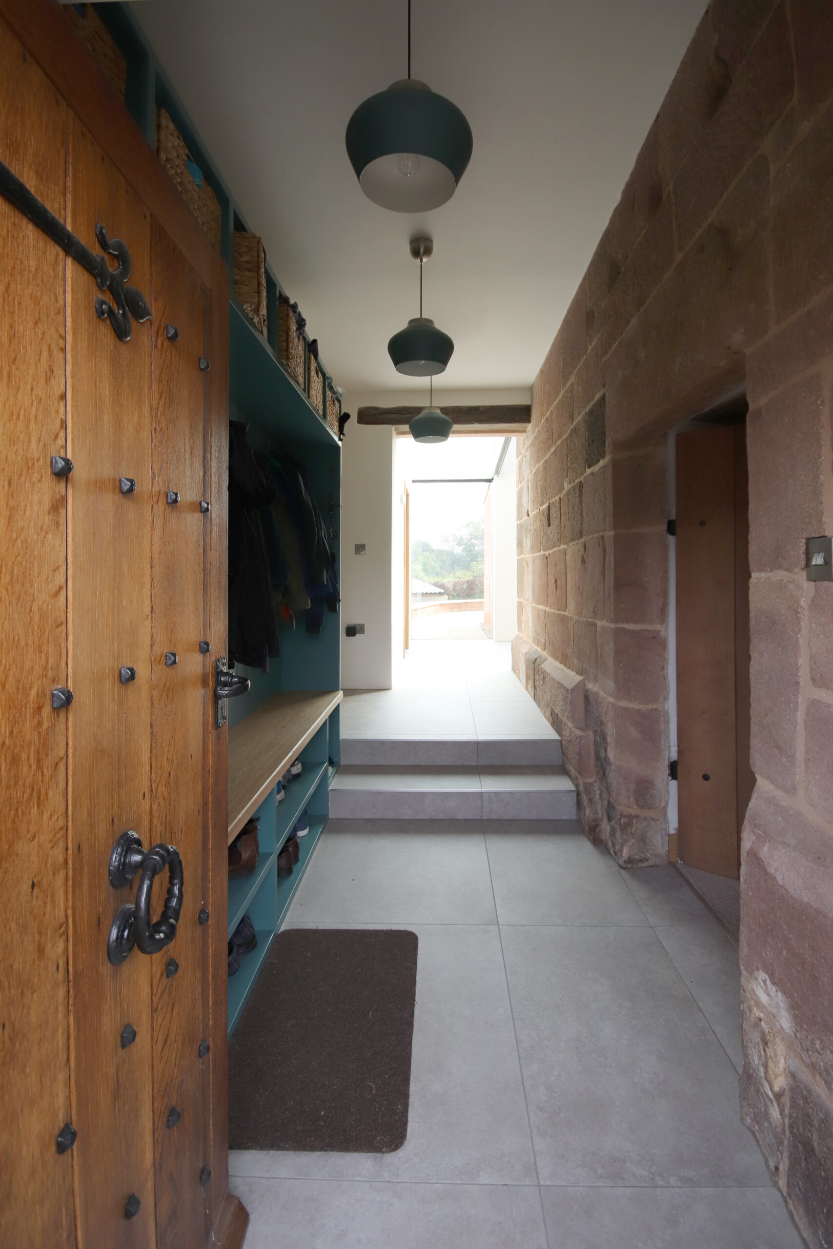 renovated entrance hall to a Grade 2 listed stone farmhouse with the original stonework fabric exposed. built in storage for boots and coats and large pendant light shades