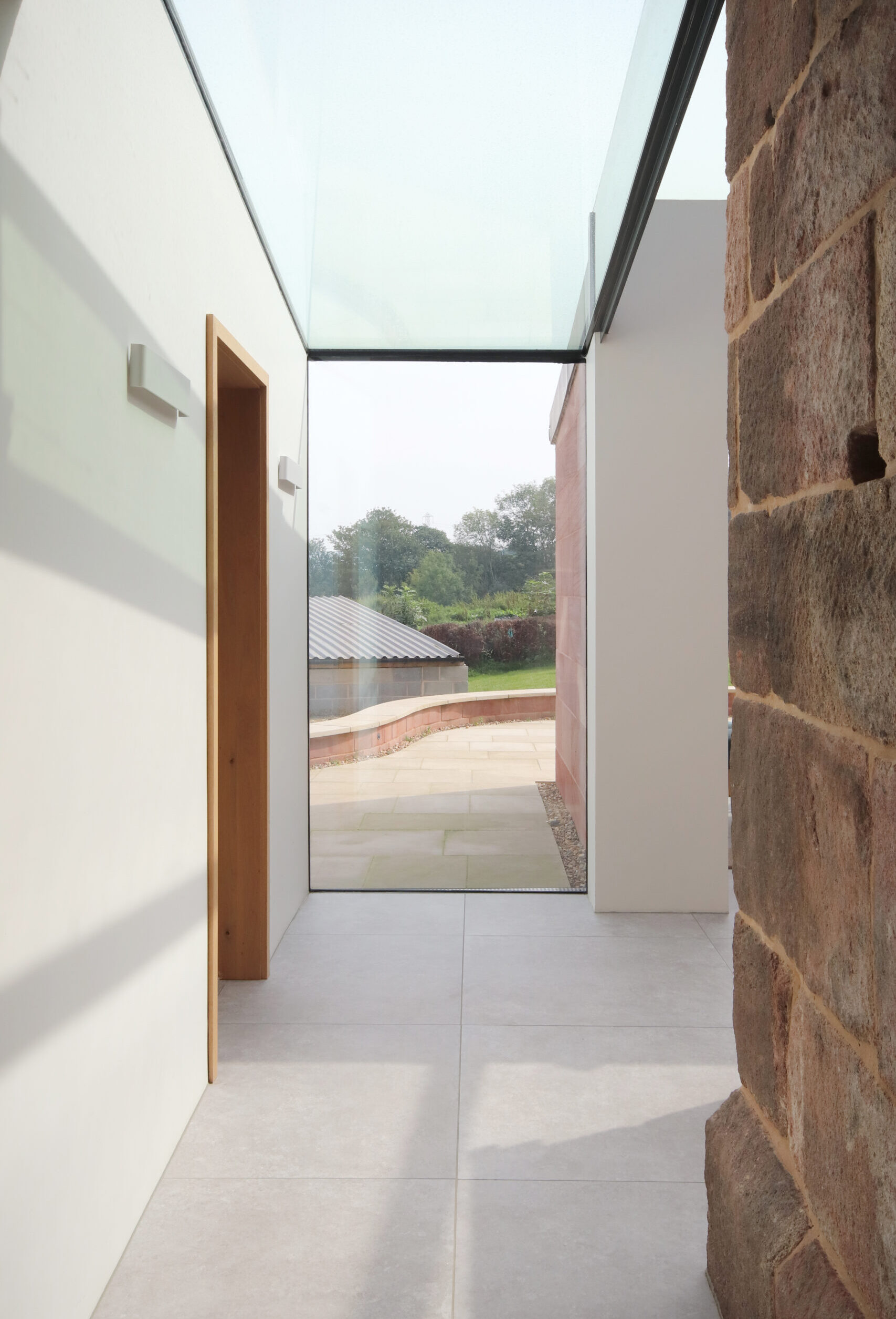 A new rear extension to a Grade 2 listed farmhouse with up and over full height glazing to preserve and highlight the original fabric of the building and highlighting the materiality with natural light and sleek additions. The openings offer views out to the rear garden, agricultural buildings and farmland beyond.