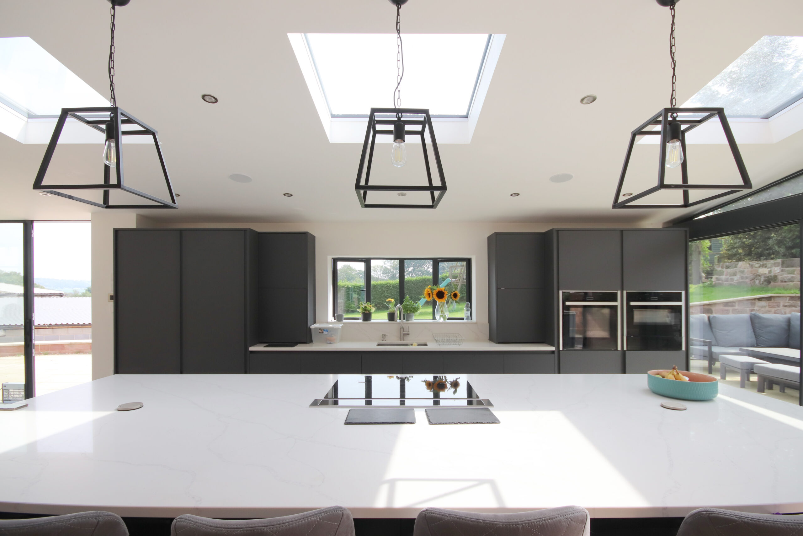 Kitchen in new rear extension to grade 2 listed farmhouse with large opening and views out to the surrounding gardens and farmland beyond. Rooflights also help bring light deeper into the building.