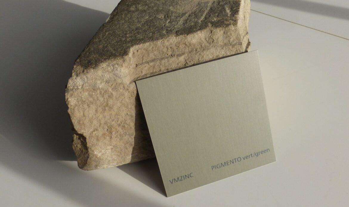 a green zinc product sample laid on a stone sample to explore materiality and textures between materials