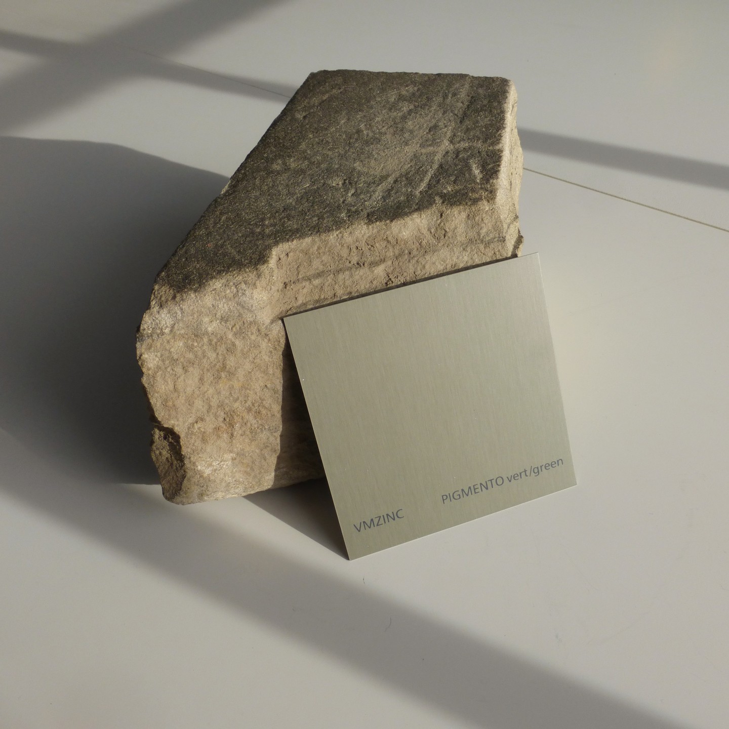 a green zinc product sample laid on a stone sample to explore materiality and textures between materials